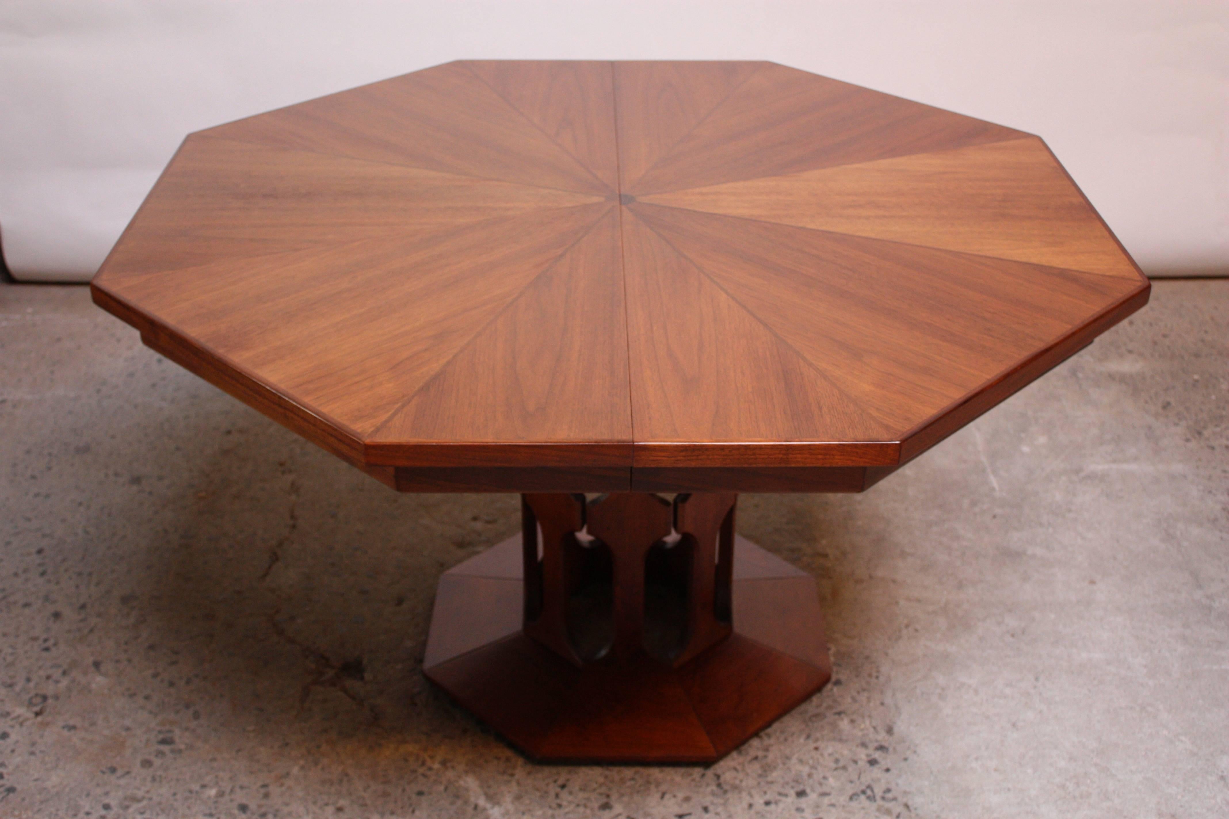 This octagonal walnut dining table (attributed to Harvey Probber) features an inlaid top on a cut-out pedestal base. This table is complete and includes all three original leaves. The pedestal base can support the top with one or even  two leaves