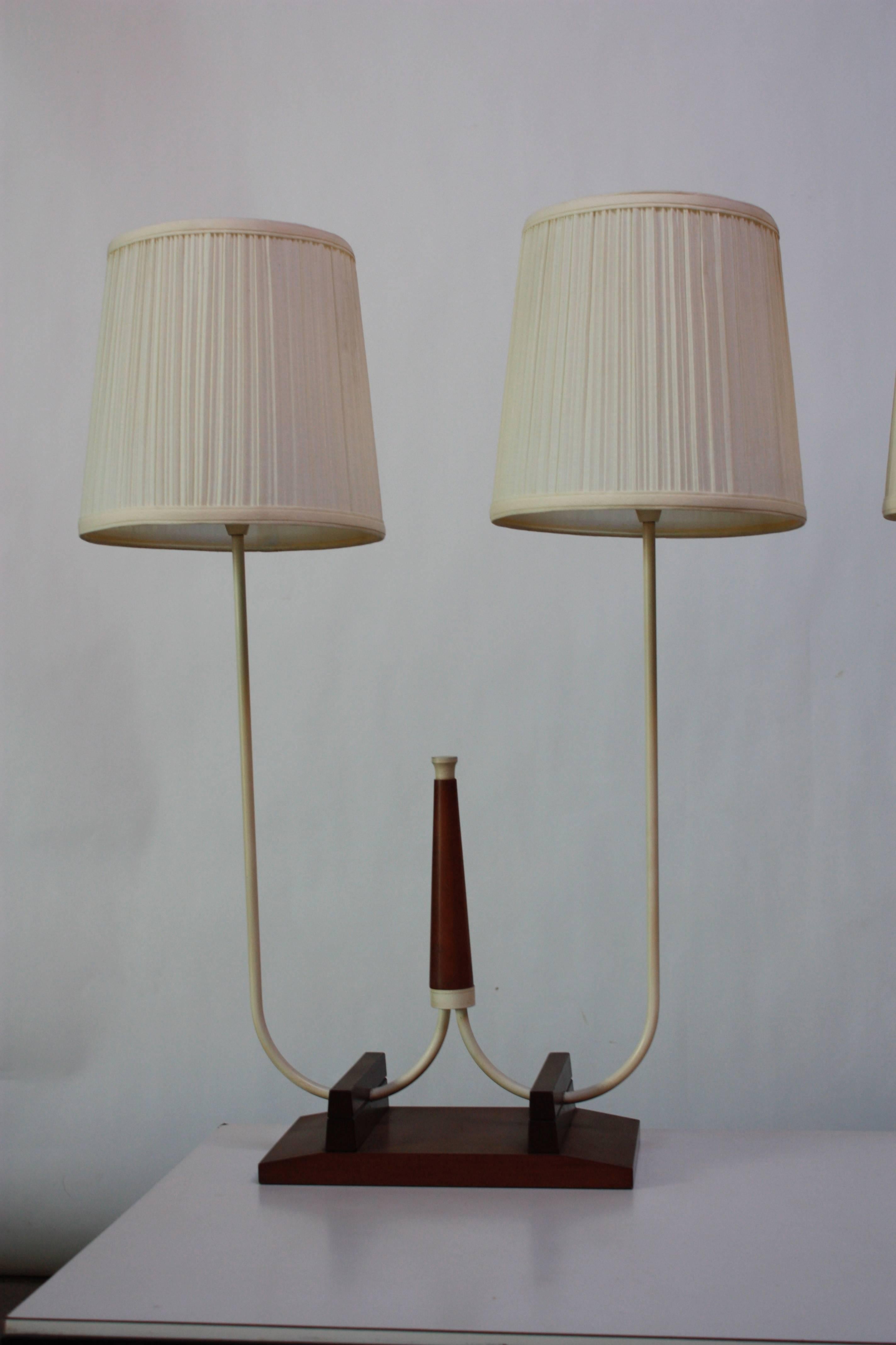 This pair of 1960s French table lamps is comprised of white enameled brass stems and finials with a walnut base and centerpiece. 
The silk shades show minor, age-appropriate wear, but the lamps themselves are in excellent, vintage condition.