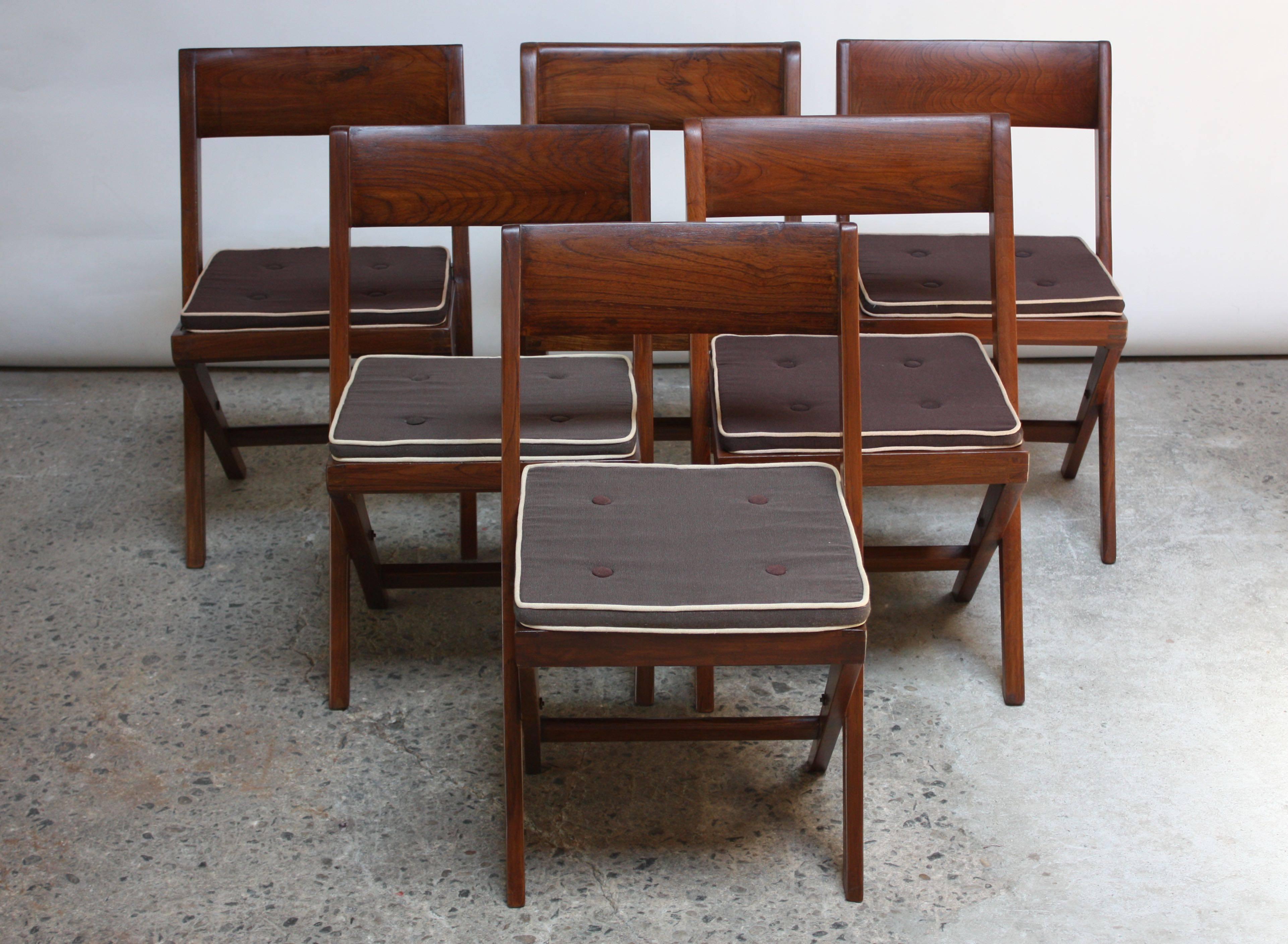 These Pierre Jeanneret library chairs (model PJ-SI-51-A) were originally designed for the University of Punjab's central library in Chandigarh in 1959. The frames are solid teak with braided cane-work seats. There are solid 'banner' style backrests
