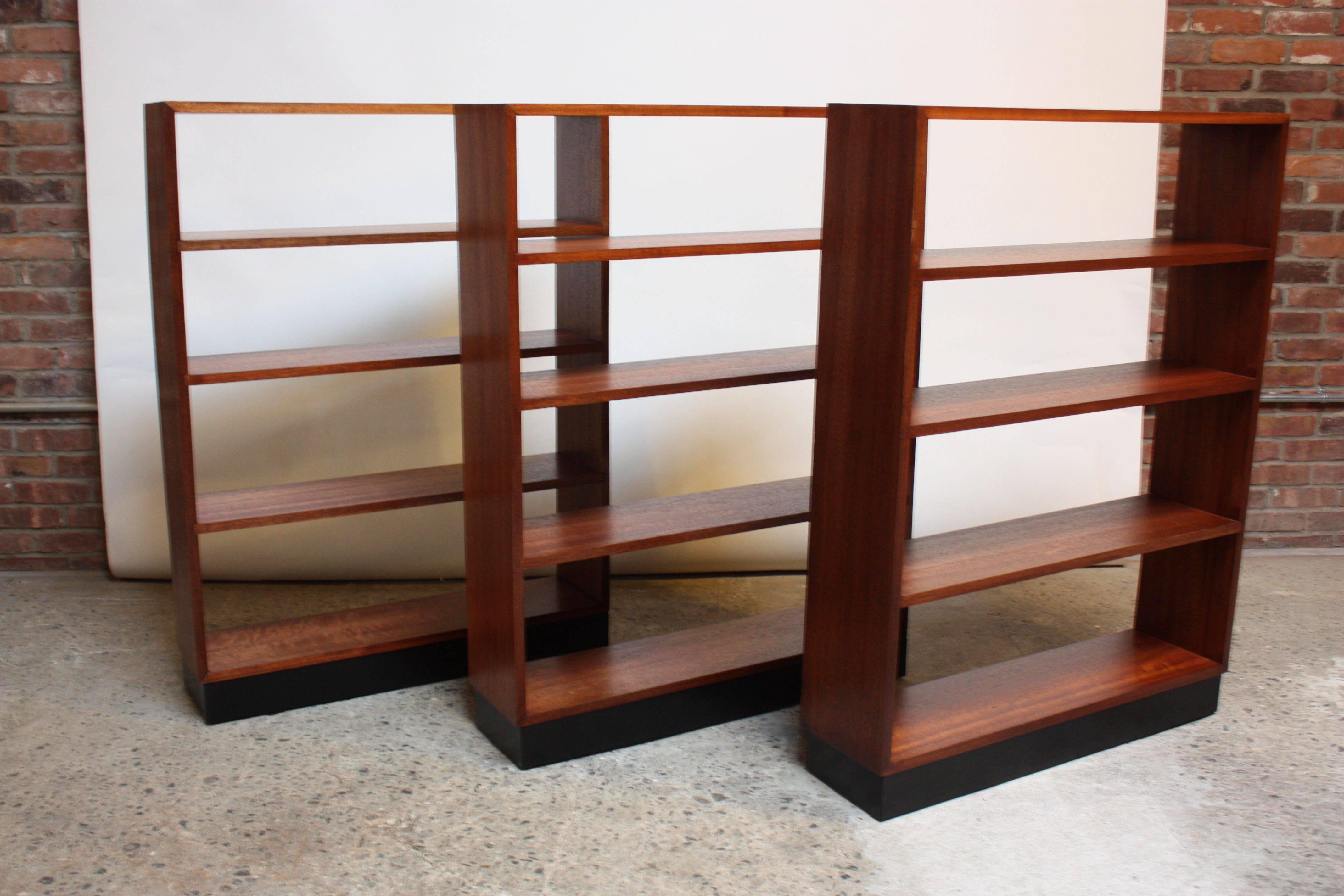 These simple open book shelves are comprised of mahogany frames atop ebonized plinth bases. The shelves are built in and cannot be adjusted. The price is for one; they are sold separately.