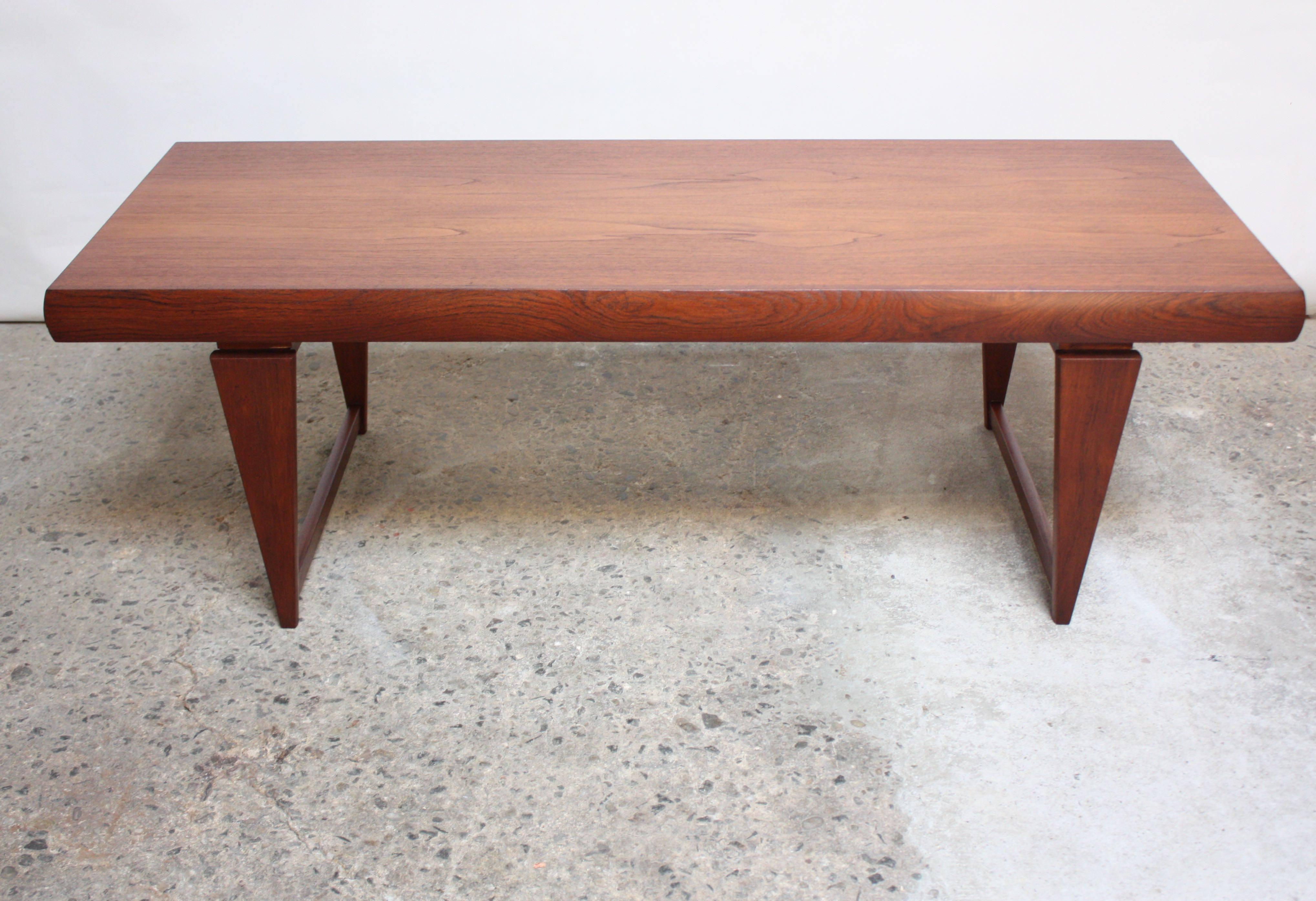 This teak coffee table features two extensions: one a draw leaf, and the other a shallow drawer. The table extensions can be pulled out individually or together. When independently extended (drawer or leaf out), the length goes from 62.75