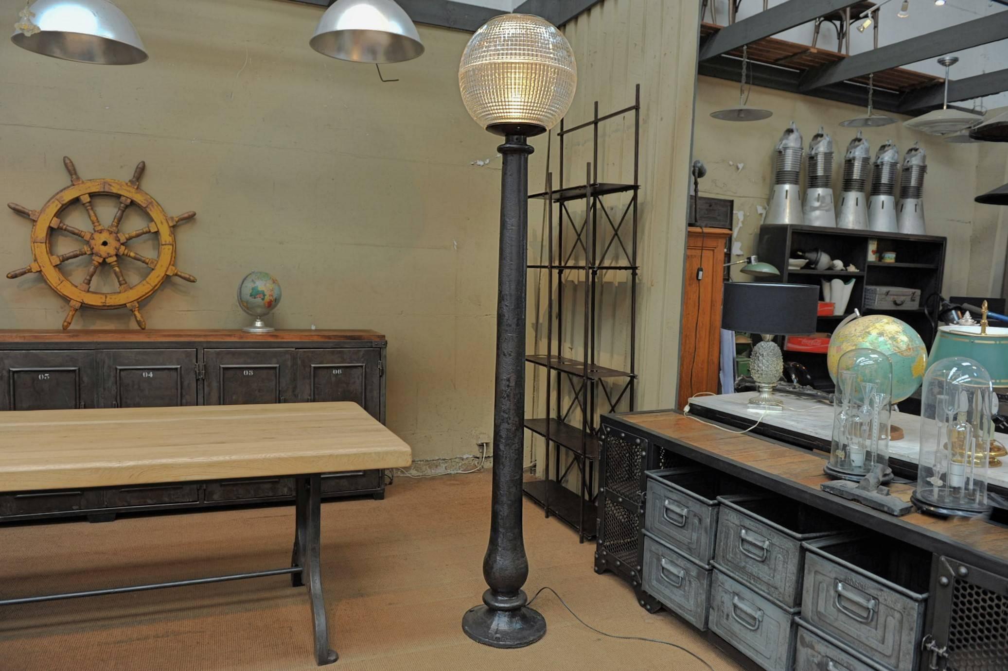 Original Holophane spherical glass and metal street light from Paris France circa 1960, turned into Industrial floor lamp with old polished cast iron column base, circa 1900.
The Holophane prismatic glass shades provides a combination of even