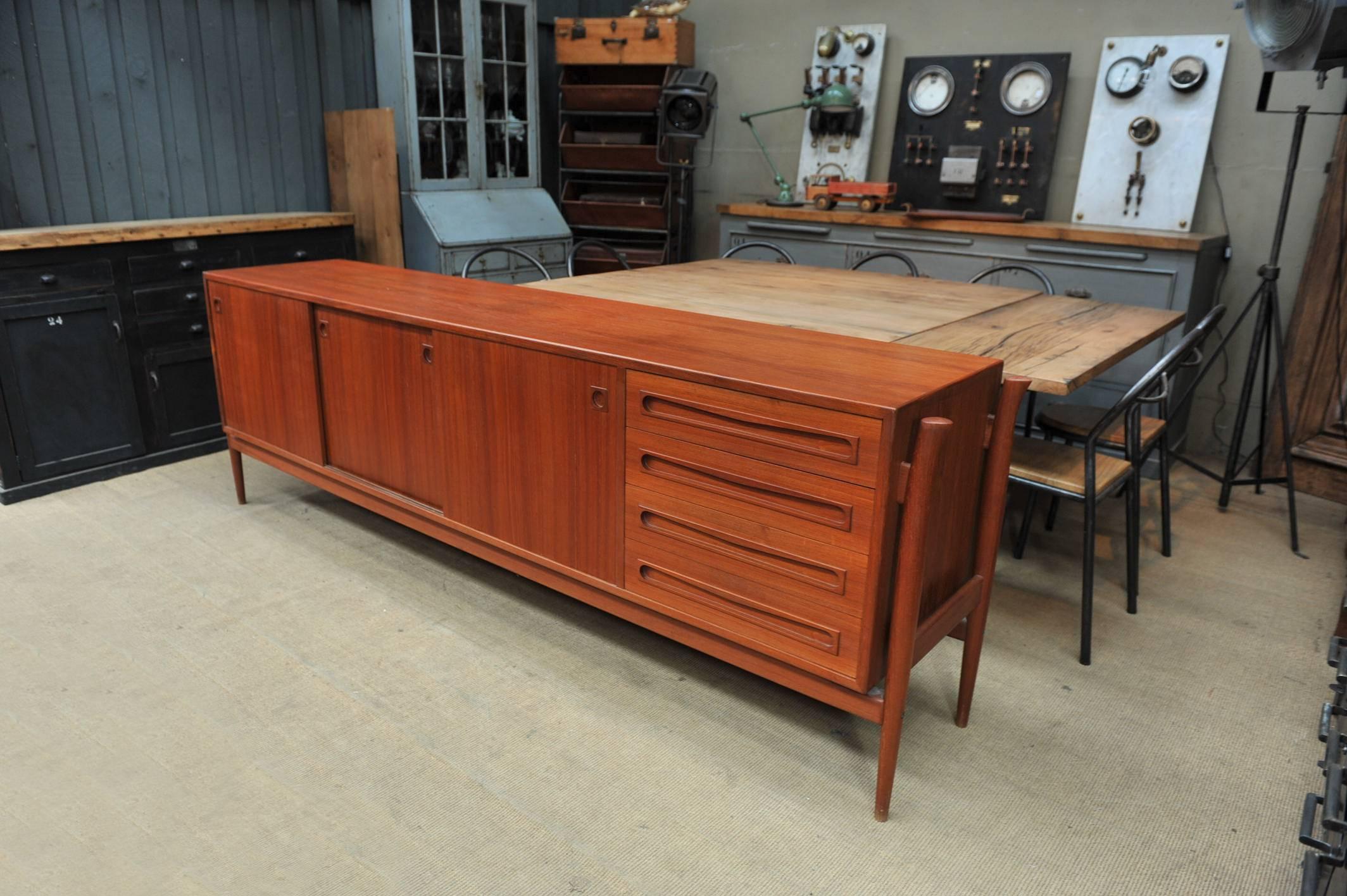 Large teak sideboard by Finn Juhl for Samcom (printed in back) with two sliding doors, four concave shaped drawers and three inside hidden shelves drawers. Great shaped feet design coming up to the sides.
All in excelent condition, circa