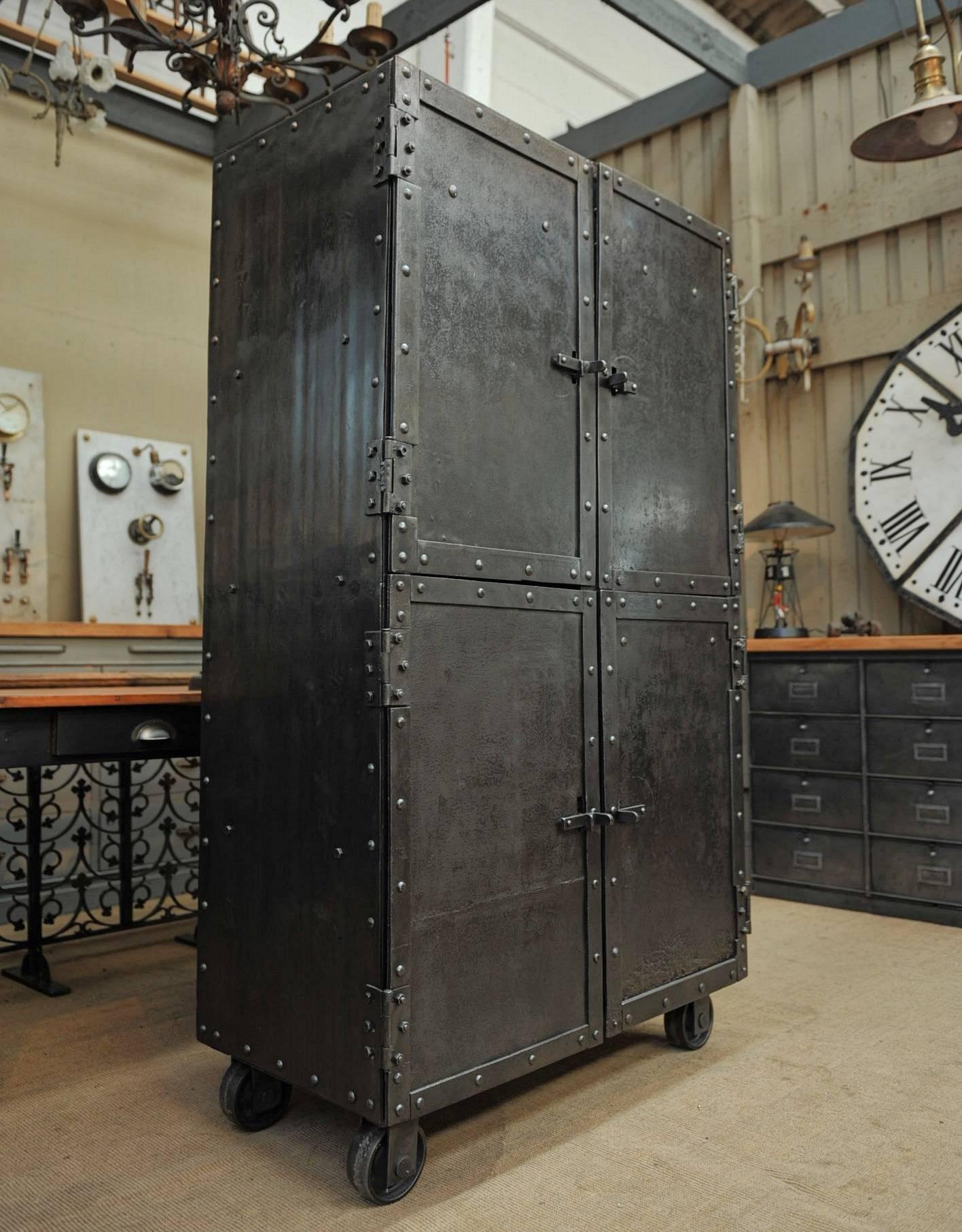 Big rivets Iron Industrial cabinet from French steel Industry with four steel wheels 
four doors and three wood inside removable shelves, circa 1900. All hand polished finish.
Weight about 280 kg.
Exceptional Four-Doors Industrial Riveted Iron