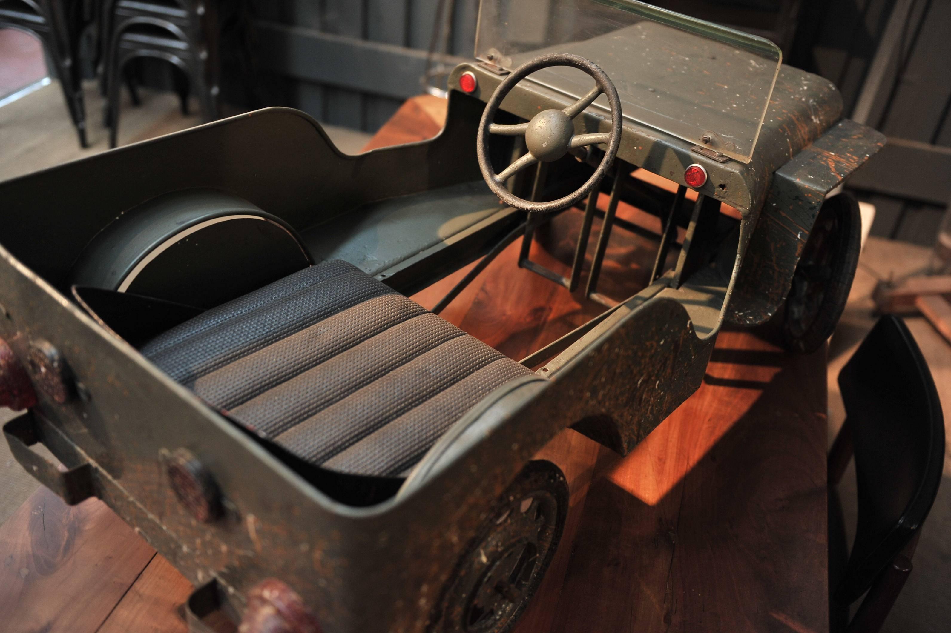 Jeep Pedal Car, manufactured in France, circa 1950.
Vintage very nice patina, repainted may be in the 1970s with a nice dirt imitation.
It has a metal body and chassis, plexiglass windshield, and big wheels with full rubber tires. Excellent