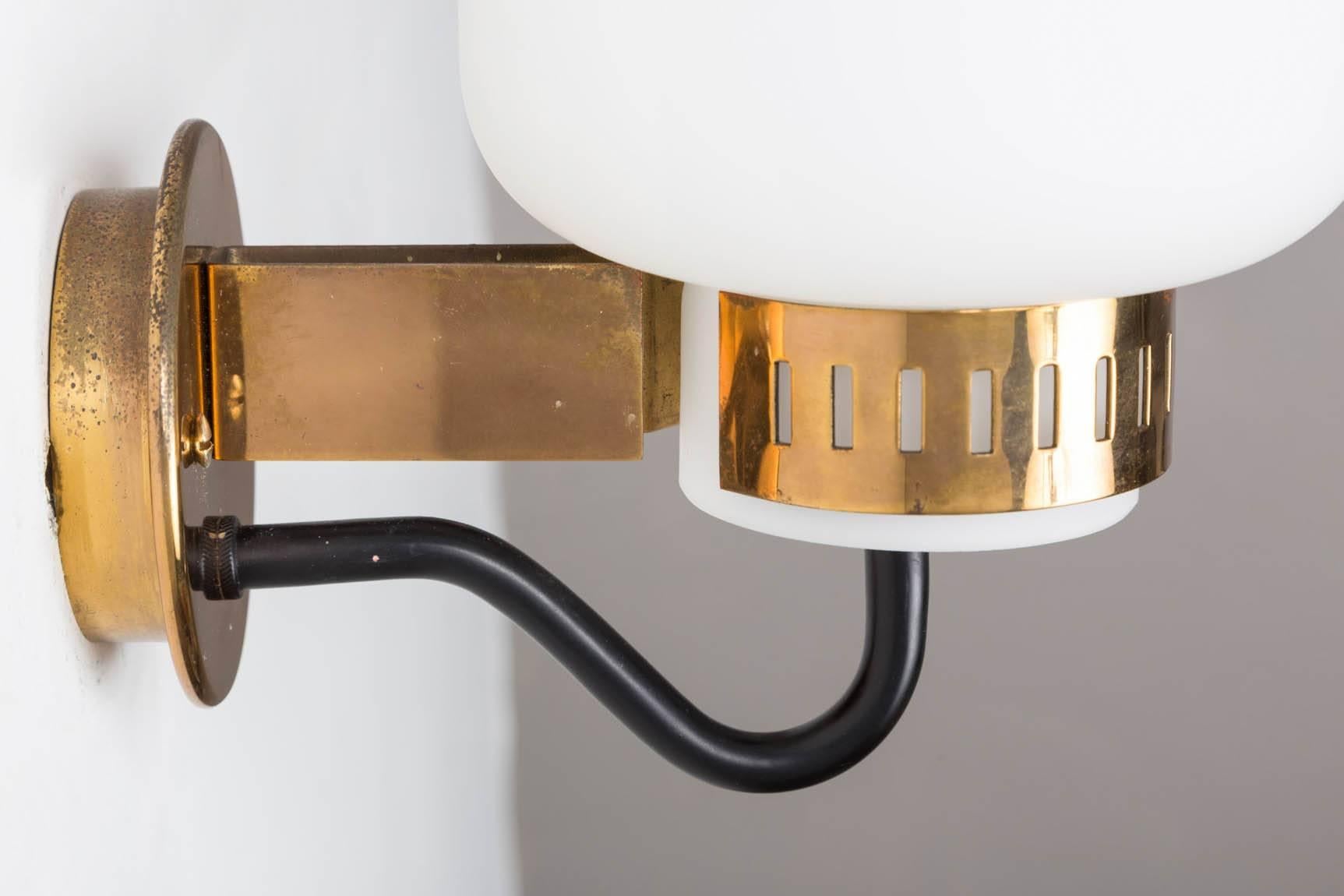 Pair of Stilnovo '2030' brass and glass sconces, circa 1965. Executed in brass, black painted metal and thick opaline glass, with original Stilnovo manufacturer's label on one lamp. A sculptural and refined design characteristic of 1960s Italian