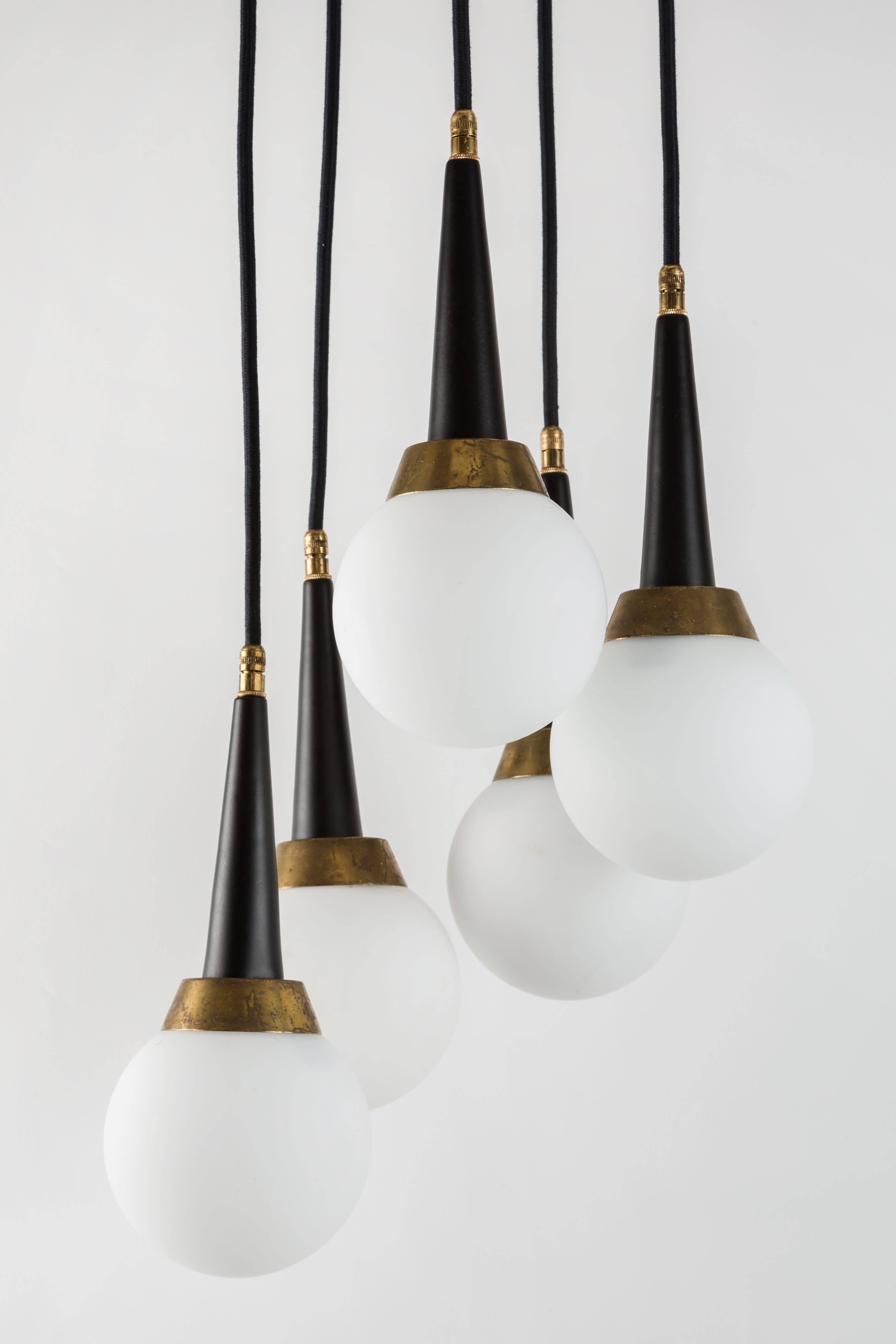 1960s Stilnovo five-globe cascading chandelier.An iconic Midcentury design executed in matte finish opaline glass, brass and enameled metal with original architectural ceiling canopy. A highly functional Italian light sculpture of attractive scale