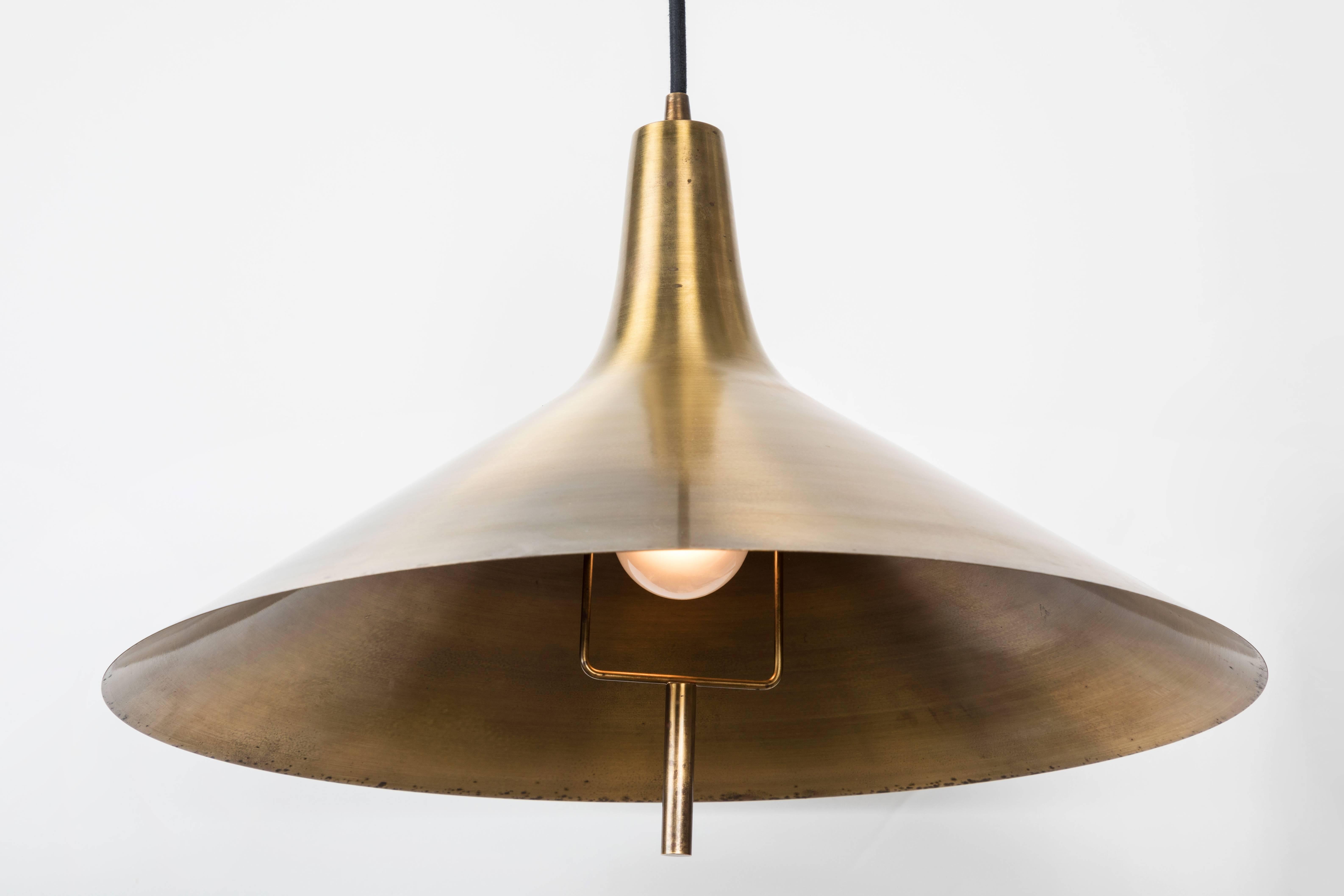 1960s brass pendant for Lyfa Denmark. A quintessentially Danish Minimalist and sculptural light executed in patinated brass and thick black cloth cord.
