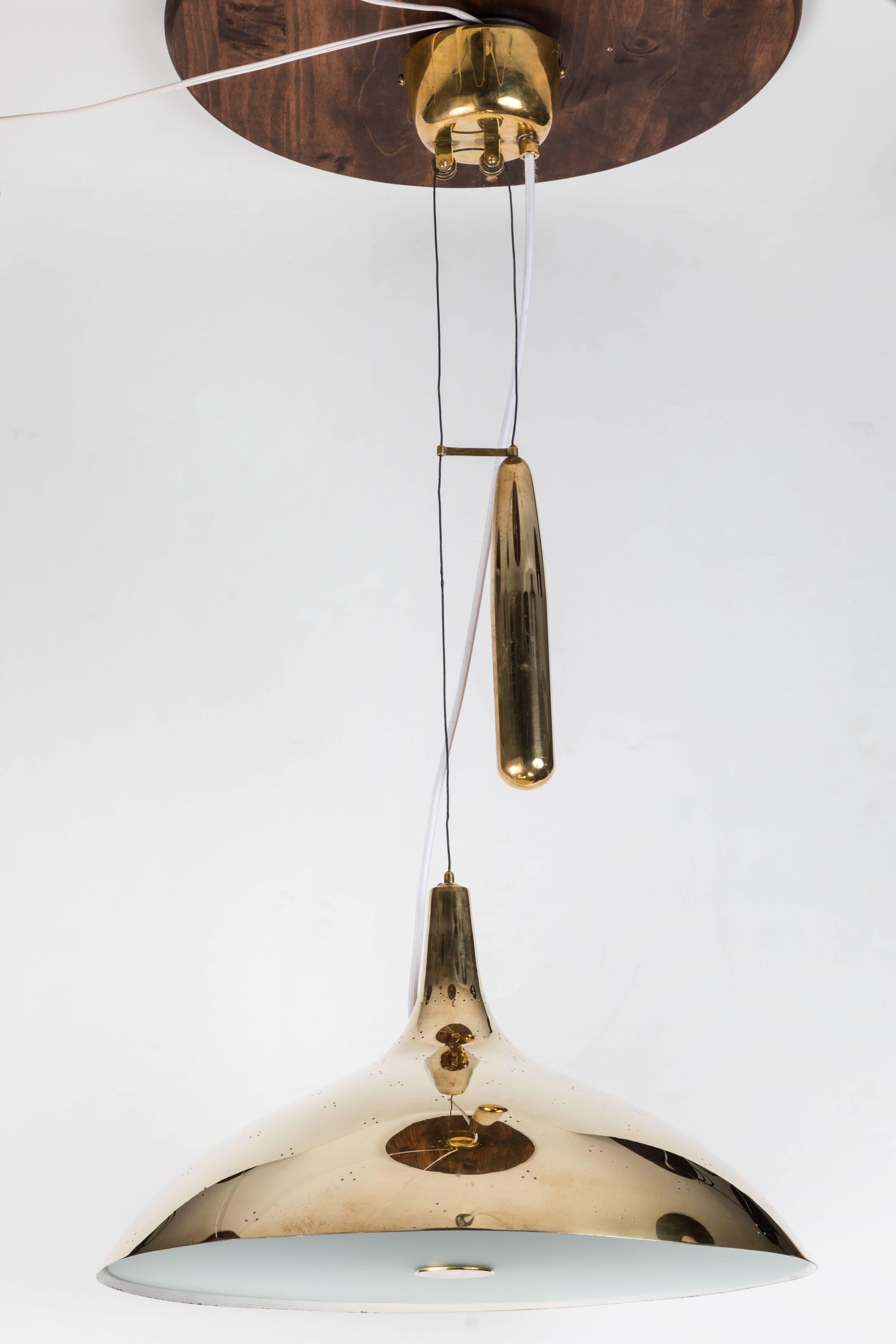 Paavo Tynell brass counterweight chandelier for Taito Oy. This rare and exceptionally refined ceiling light is executed in attractively patinated brass and opaline glass, and can be raised and lowered using its ingenious counterweight and pulley