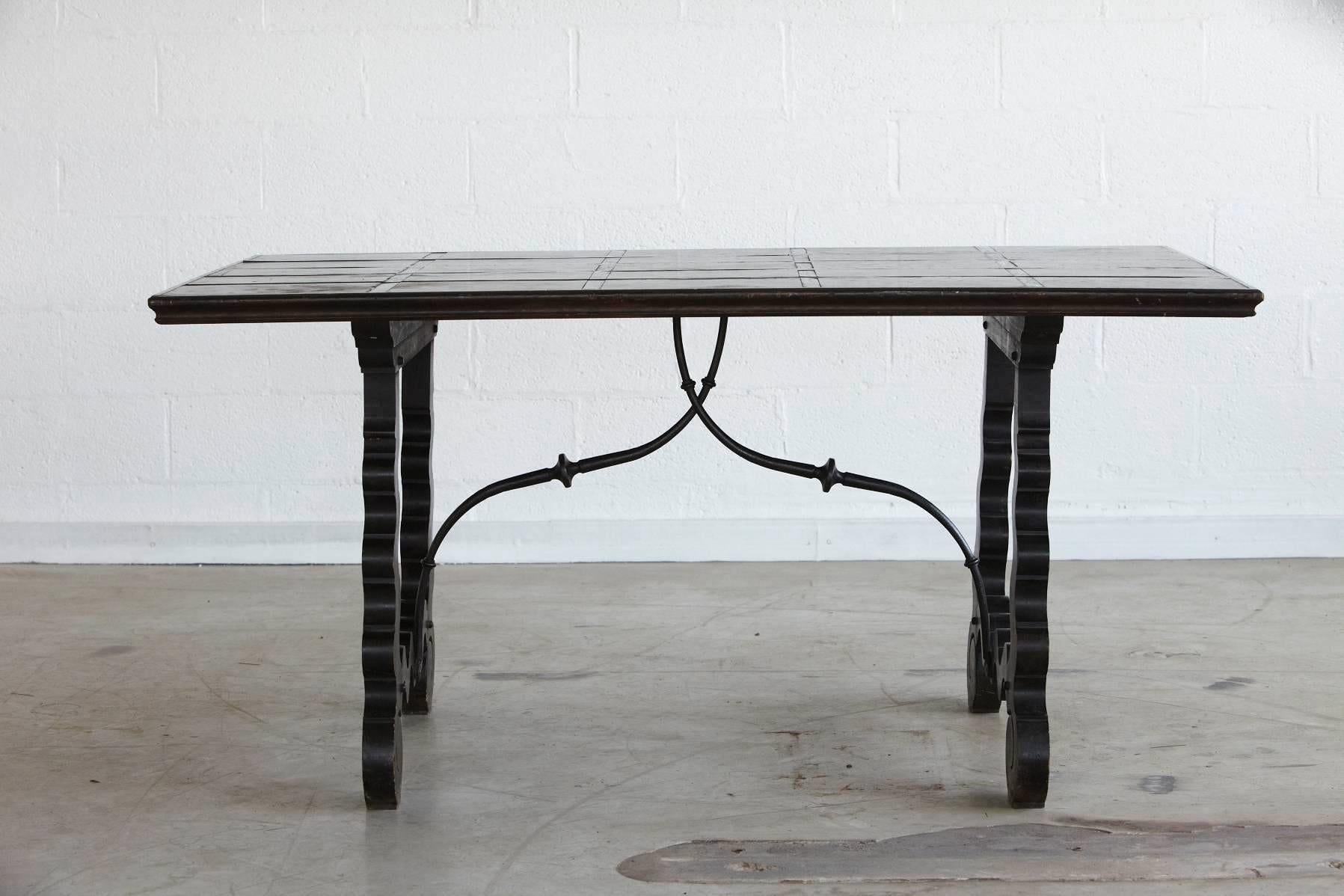 Spanish Colonial style walnut trestle table with carved legs, scrolled iron stretchers and decorative iron inlays in tabletop, circa 1960s.
Perfect as small dining table, library table or generous desk.
  