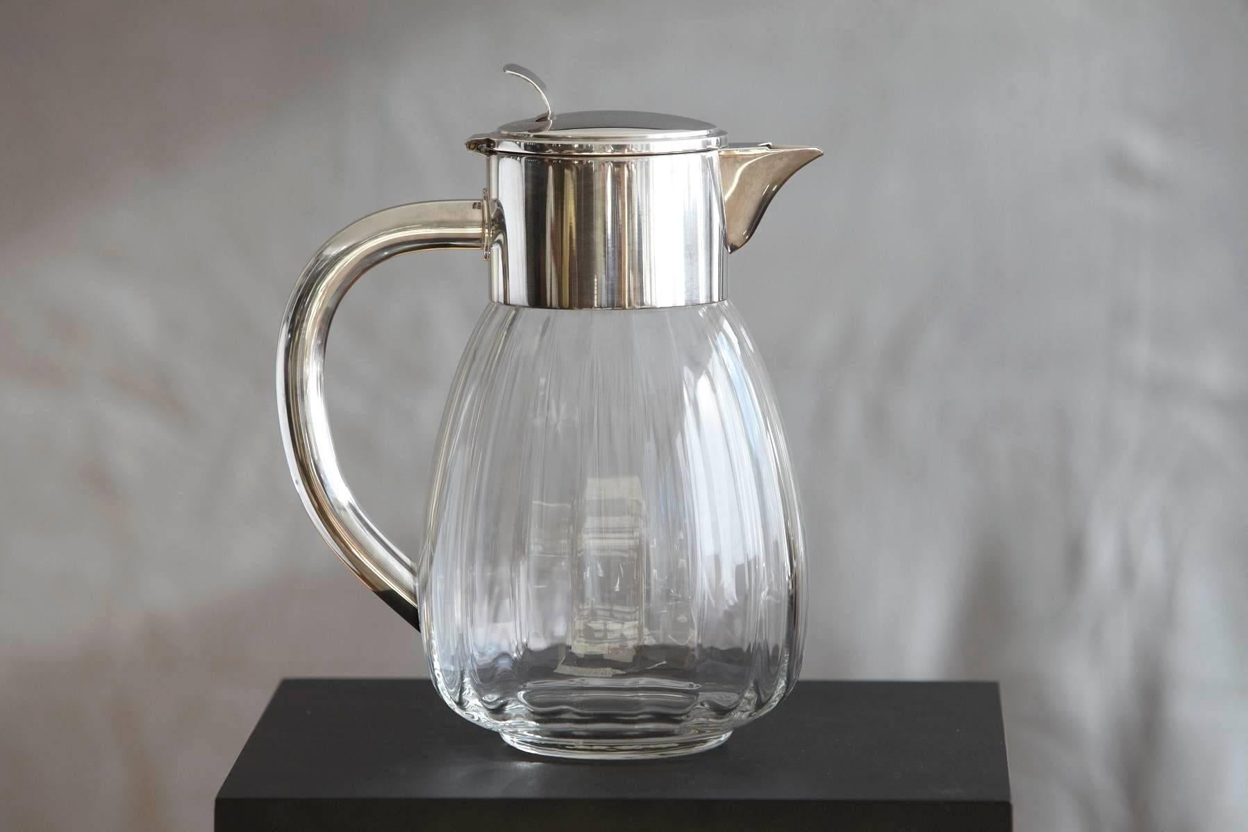 Vintage midcentury silver plate lidded and glass water carafe, made in Germany.

The Eisenberg-Lozano Co based in New York City was founded in 1953 by Arthur Eisenberg and Neal Lozano. The lid is marked with the Eisenberg-Lozano company's hallmark