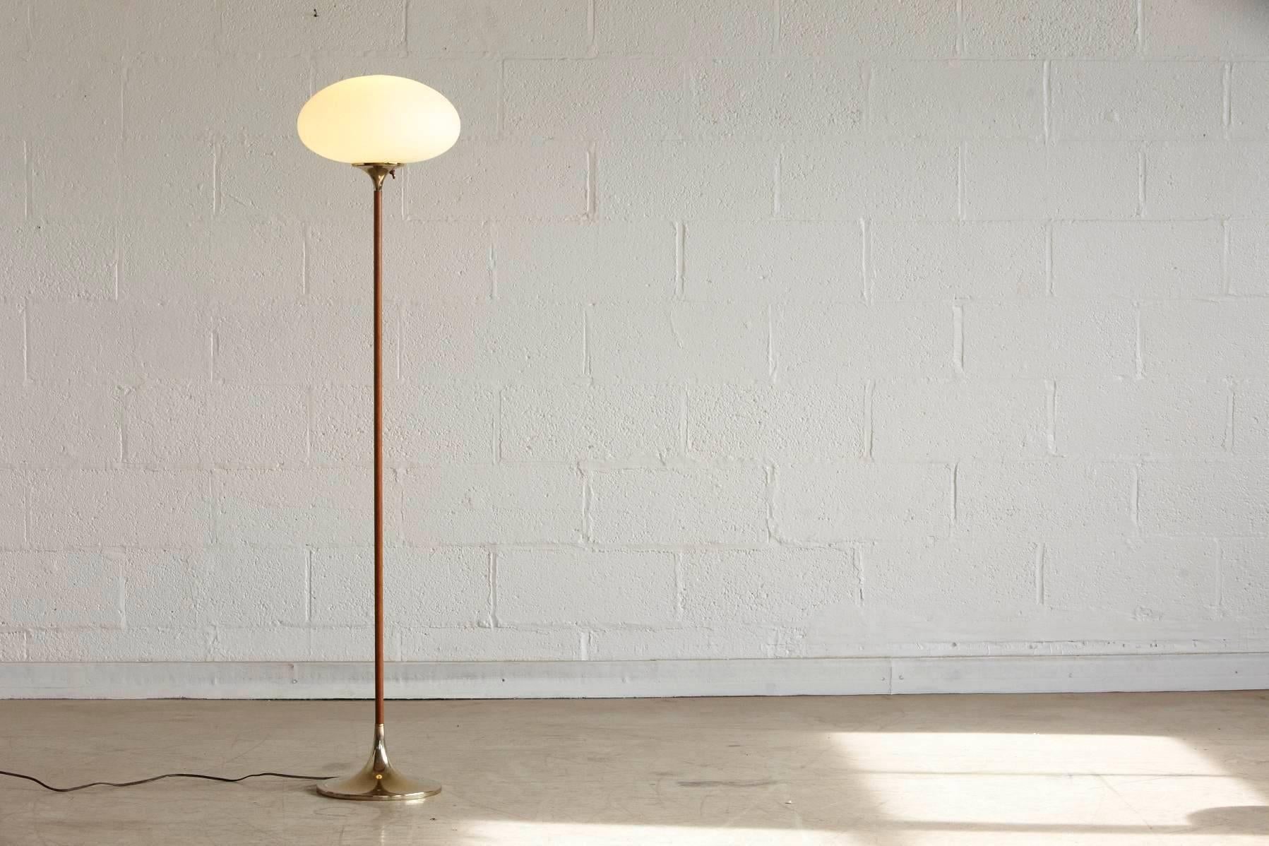 Elegant laurel mushroom floor lamp. Frosted blown glass shade in excellent condition on a brass neck which merges into a slender walnut stem which connects with a polished brass base.
Dimensions: Base diameter 10