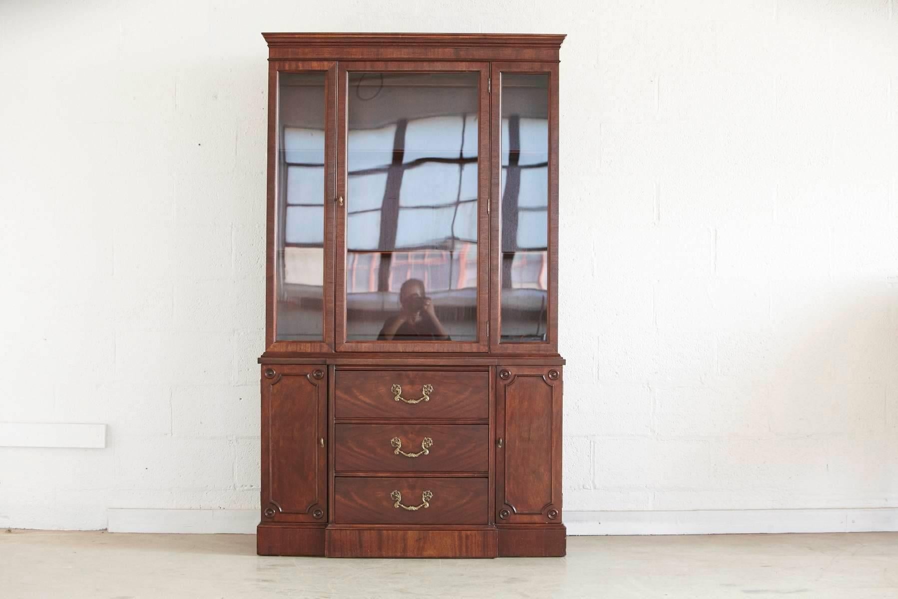 Walnut china cabinet or hutch, features a three-drawer cabinet with brass pulls, two doors and a hutch with one large glass door.