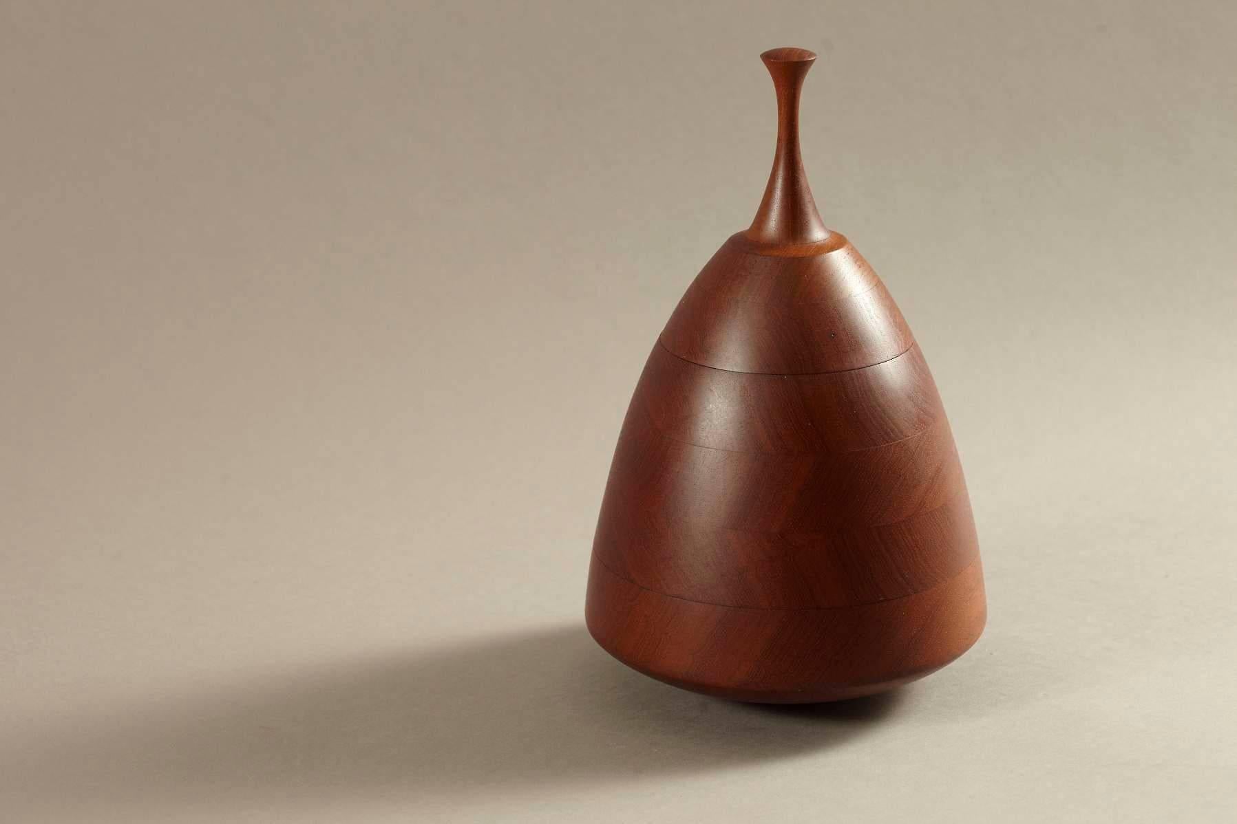 A conical lidded teak vessel with a gracefully shaped finial, signed Dunbar.