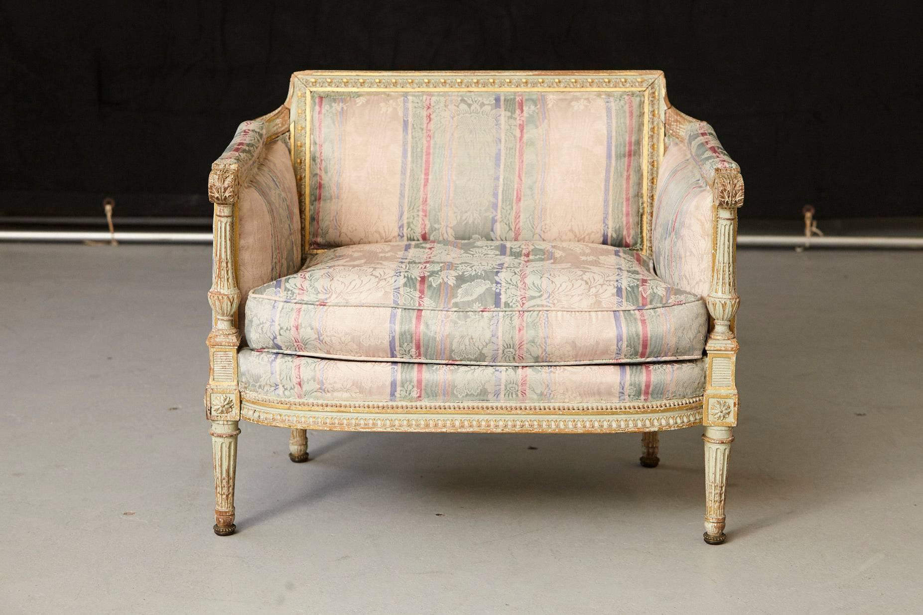 Beautiful French distressed paint and gild decorated fauteuil in the style of Louis XVI.
Some paint and gild loss, some cracks to frame, water and fading to upholstery,
please refer to the detailed pictures. 
Still a beautiful piece in it's as is