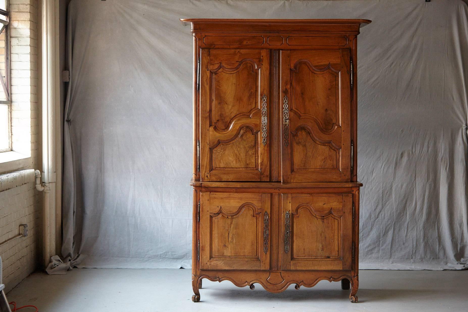 Extraordinary French 18th century Louis XV style fruitwood cabinet a deux corps. The upper section recessed and with a molded overhanging cornice above a simple paneled frieze and twin decoratively paneled cupboard doors enclosing shelving covered