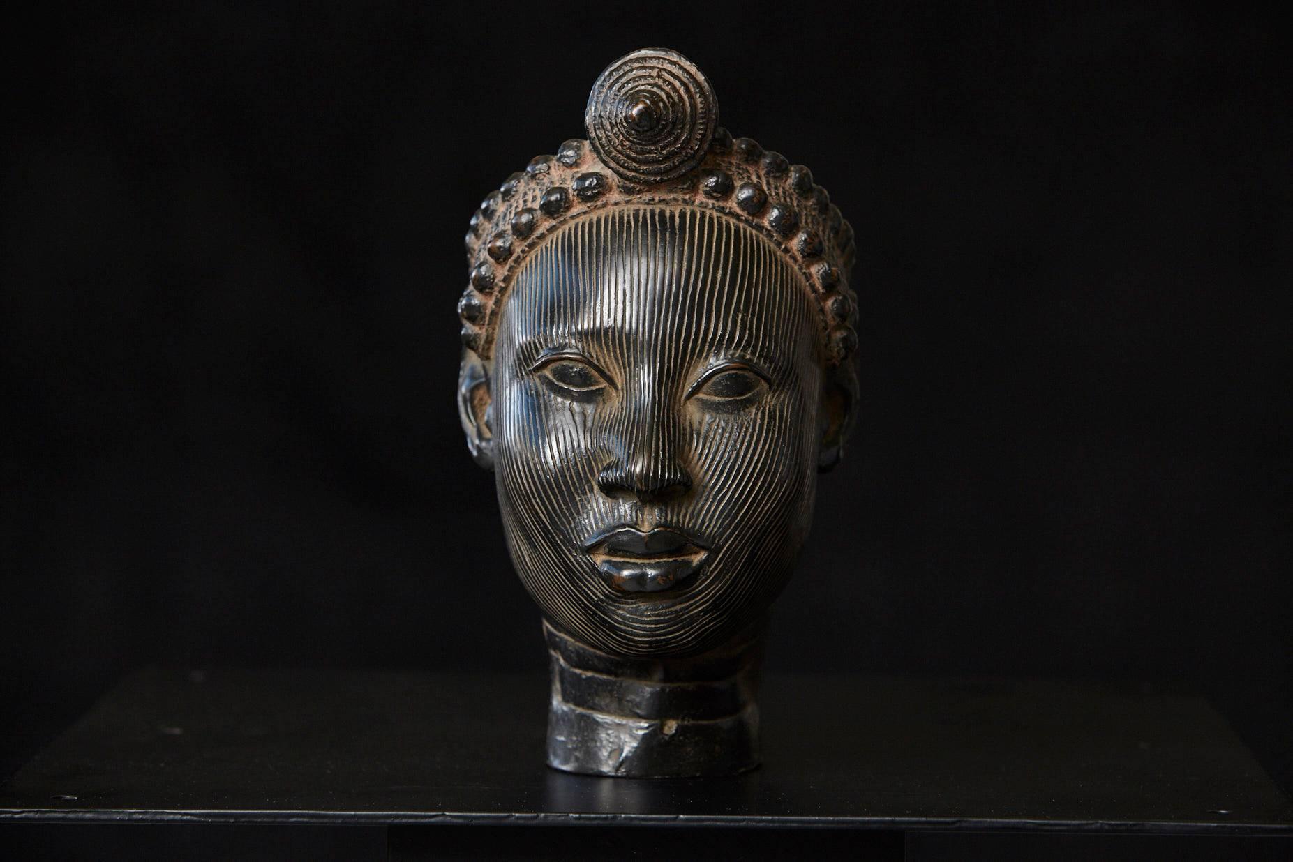 L'excellente réplique en céramique d'une tête avec une couronne, représente l'une des dix-huit sculptures en alliage de cuivre qui ont été mises au jour en 1938 à Ife au Nigeria, le centre religieux et ancien centre royal du peuple Yoruba.
Les