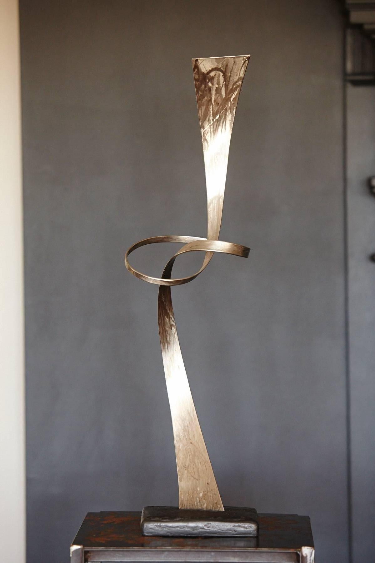 Beautiful airy steel sculpture showing a steel ribbon that tapers from wide to narrow to wide again with a joyful, light move in form of a knot in the middle.
The hand colored patina and the structures of the brushed metal give the sculpture an