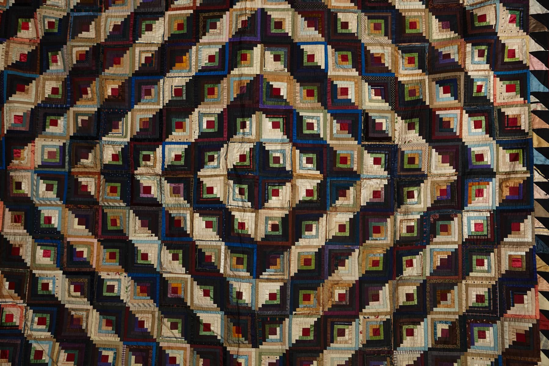 A multitude of blocks approximately 3 1/2 square are pieced of narrow 'log' strips of silk. These are arranged by light and dark tonality to create the expanding concentric diamond shapes across the quilt surface that are characteristic of this