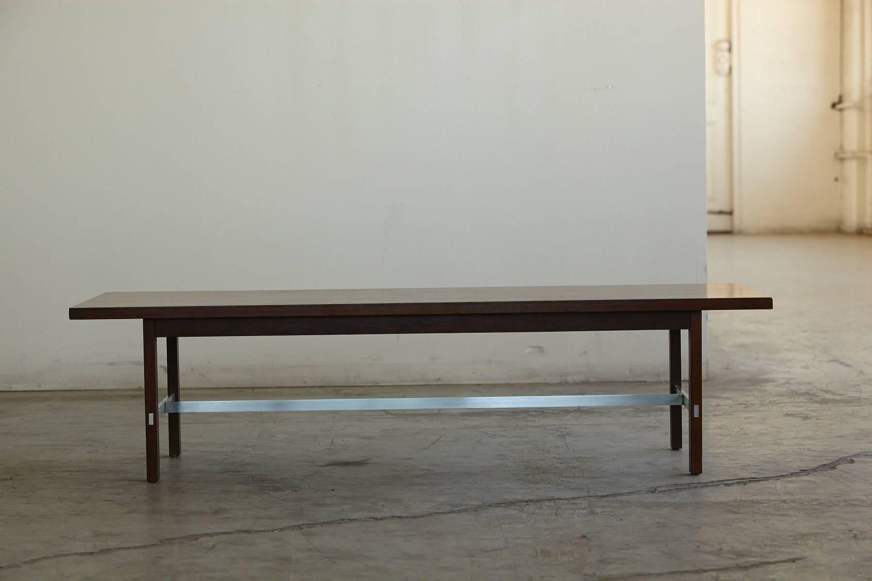 Beautiful, low, rectangular coffee table in walnut and thin strips of aluminum, who cross brace into the walnut legs for added support, which give the table a light weight flow. The aluminum strips are in excellent condition.
This modern coffee