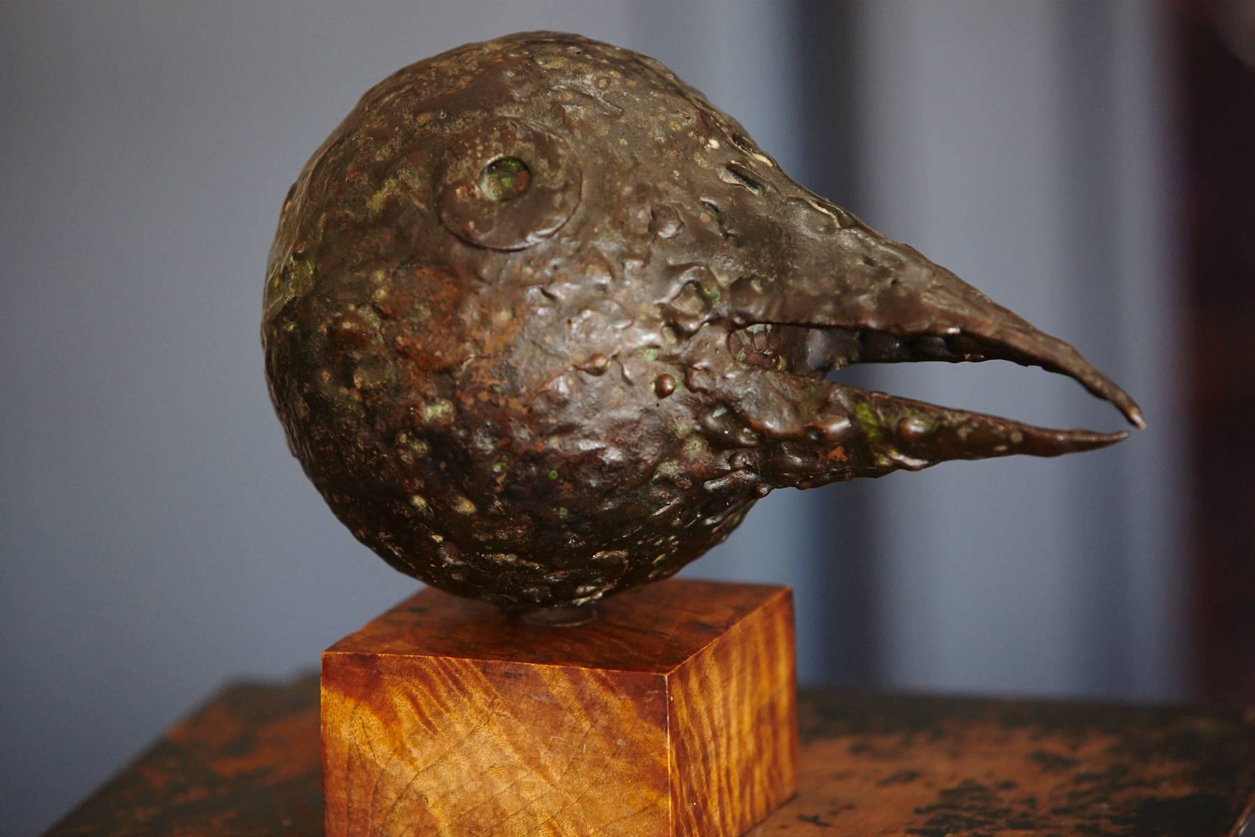 Brutalist style bronze sculpture showing a bird's head with a long beak mounted on a wooden base, circa 1960s. Artist unknown.

