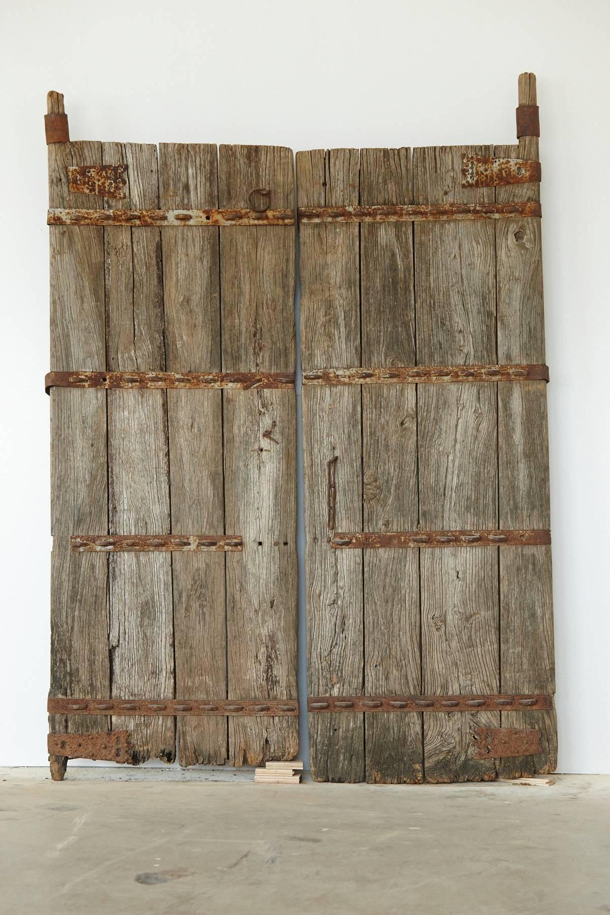 Pair of unrestored Chinese gate doors in heavy, reinforced solid oak with hand-forged metal applications. The depth of the doors is 7