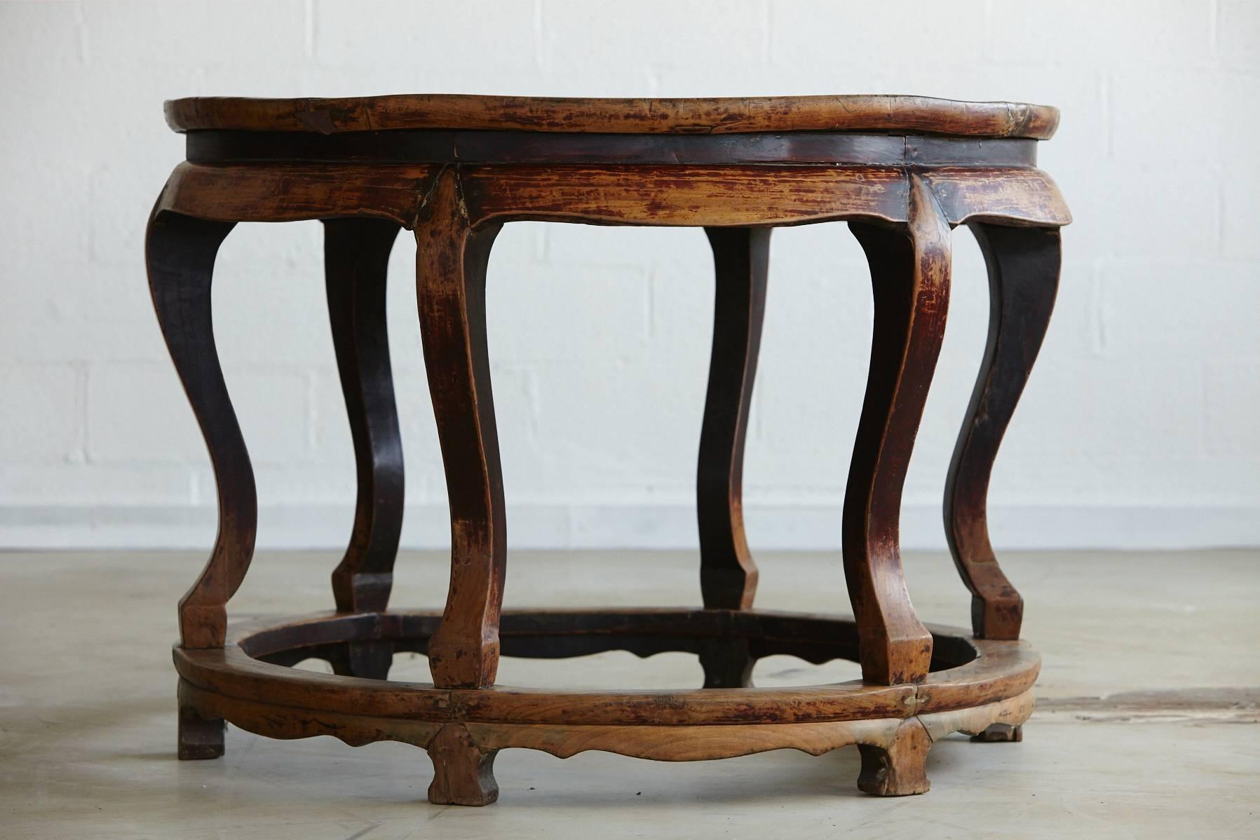 Antique Chinese Export hand carved round elm wood center table with 6 cabriole legs mounted on a round stretcher. 
The table has a very nice patina, wax polished, with little dents and dings,  slightly uneven areas within the top, a well lived