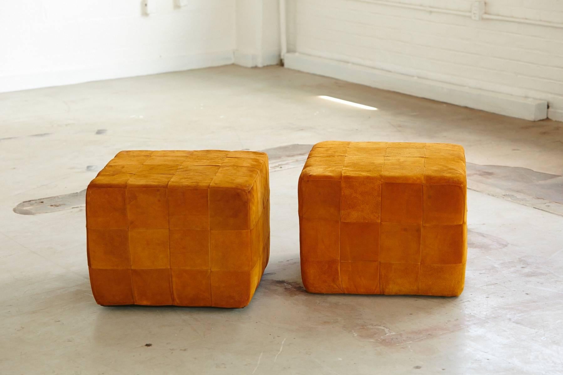 Nice pair of square cognac colored buckskin cube ottomans made out of square leather patches. Leather has great patina, the cubes have been refurbished with new foam and a very solid in seat quality and holding the form.
Sticker on bottom saying -