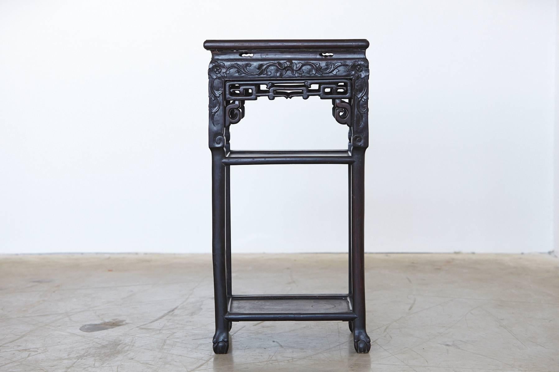 19th century Chinese rectangular hardwood table with decorative hand-carved and pierced ornaments on the panels and the legs, rectangular marble inset, two shelves and square legs ending in claw feet. Beautiful details, great quality of the carving,