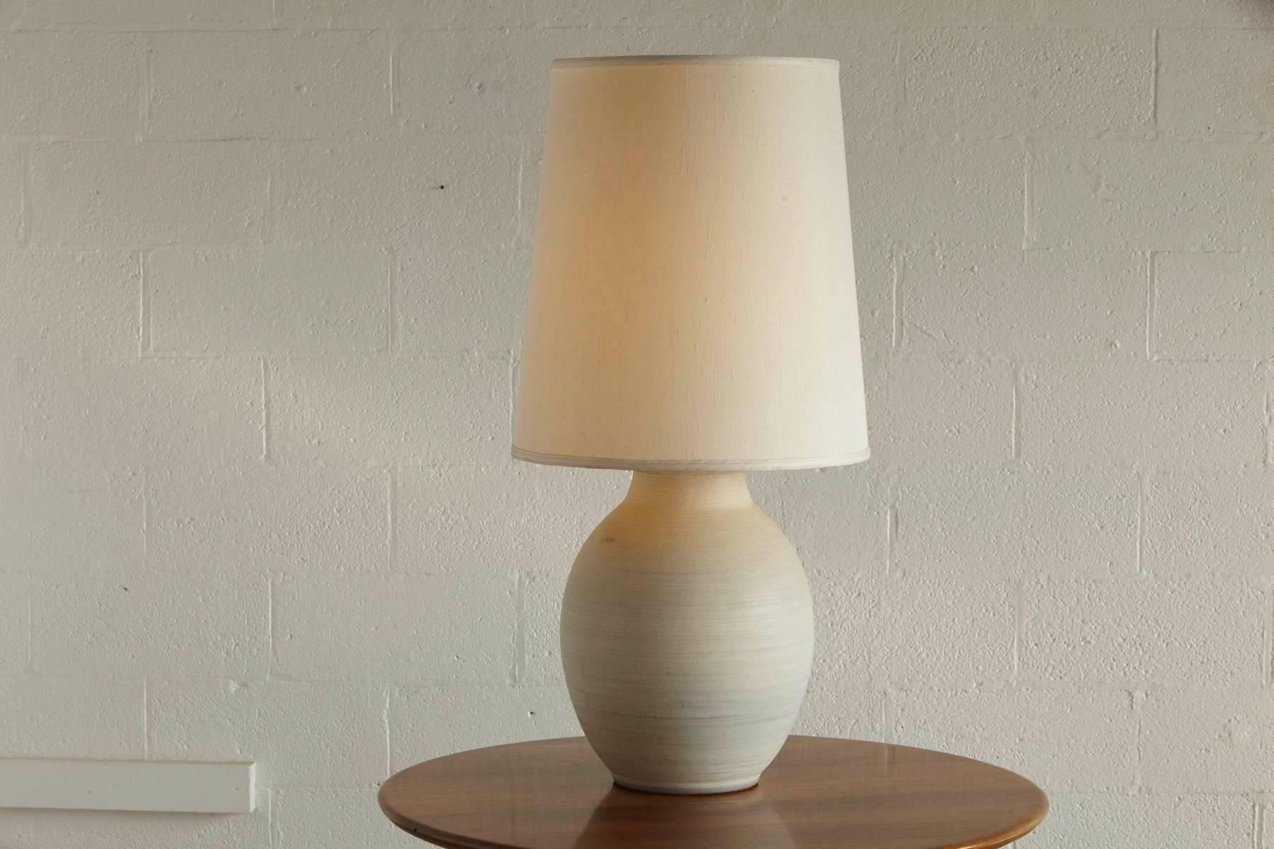 Large Italian cream colored ceramic lamp with tall silk shade.
Nice tall table lamp in very good condition from the 1970s.
Dimensions:
Diameter base 13 in x height to socket 21 in - height to finial 39 in.
Diameter shade 18 in.