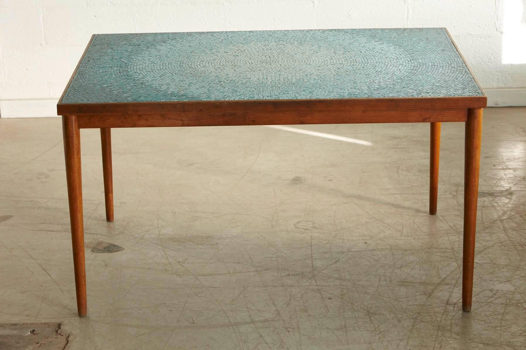 Beautiful circular degrading aquamarine pattern for this tile top dining or accent table attributed to Jane and Gordon Martz for Marshall Studios.
The underlying table base for the mosaic tiles is a solid wood construction, framed by a thin walnut