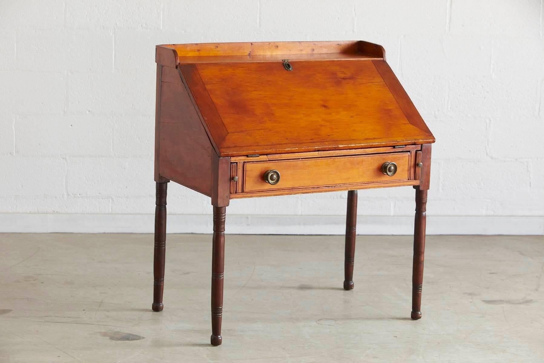 Antique pine drop-leaf secretary or desk. The secretary features plenty of compartments and small drawers, as well as one large drawer with brass pulls.
The lock is missing, great patina.