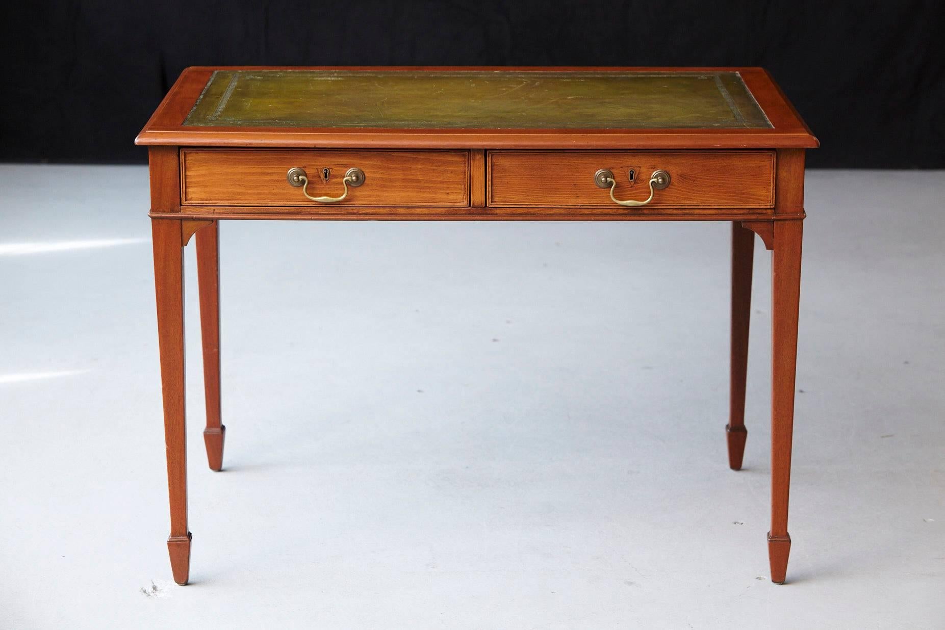 Petite French walnut desk with a light finish. Olive green leather top with gold tooling, two drawers with brass handles, raised on tapered legs with spade feet.
Some scratches to the leather surface, please refer to the detailed photos.