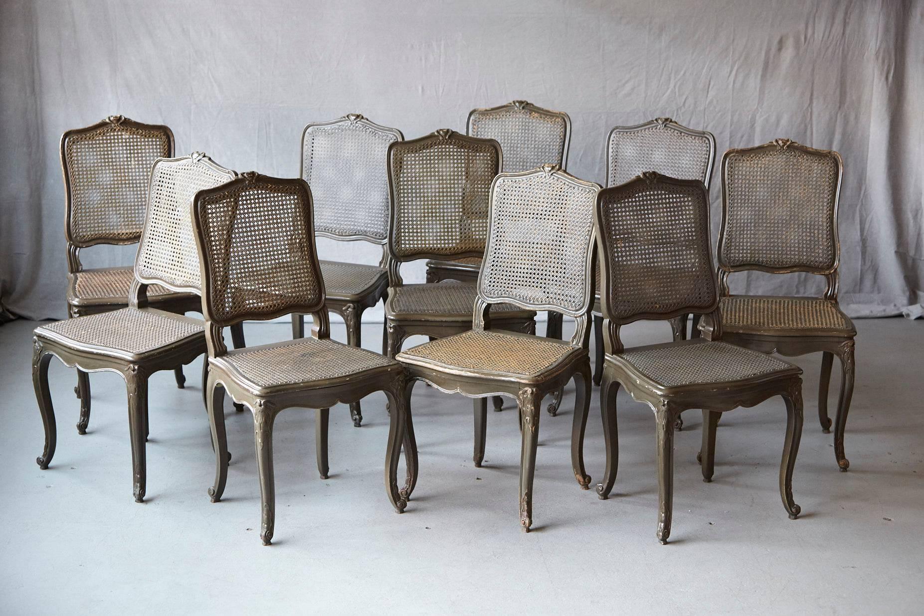 Set of ten early 20th century French Provençal country style dining chairs with caned backs and seats in hunting green paint finish. Raised on cabriole legs with carved knee mounts. All caned seats have a wood support for the sitting surface.
The