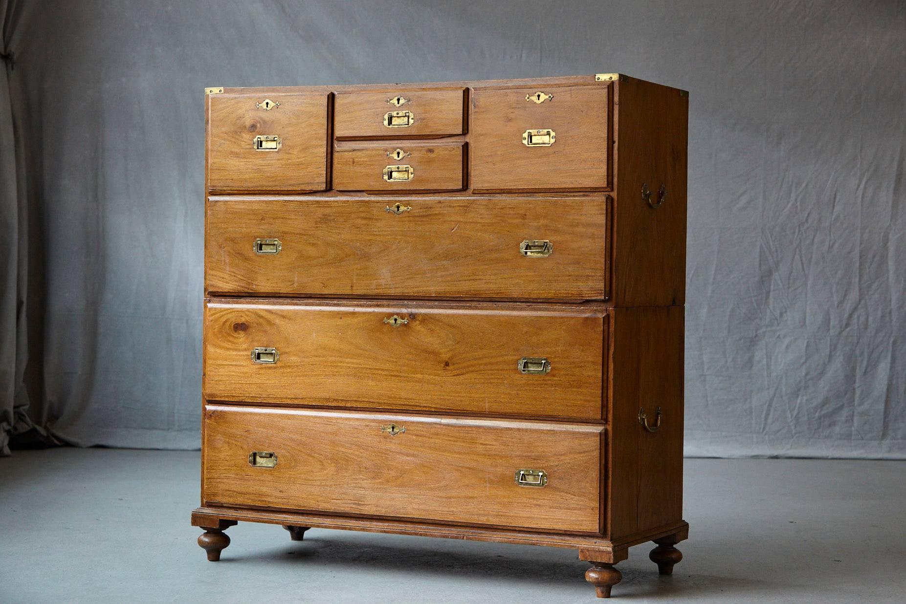 Late 19th century English Campaign chest of drawers with brass binding, brass recessed handles and brass side handles, raised on removable legs.
4/3 drawer configuration with three long drawers and four small drawers.
There has been some repair