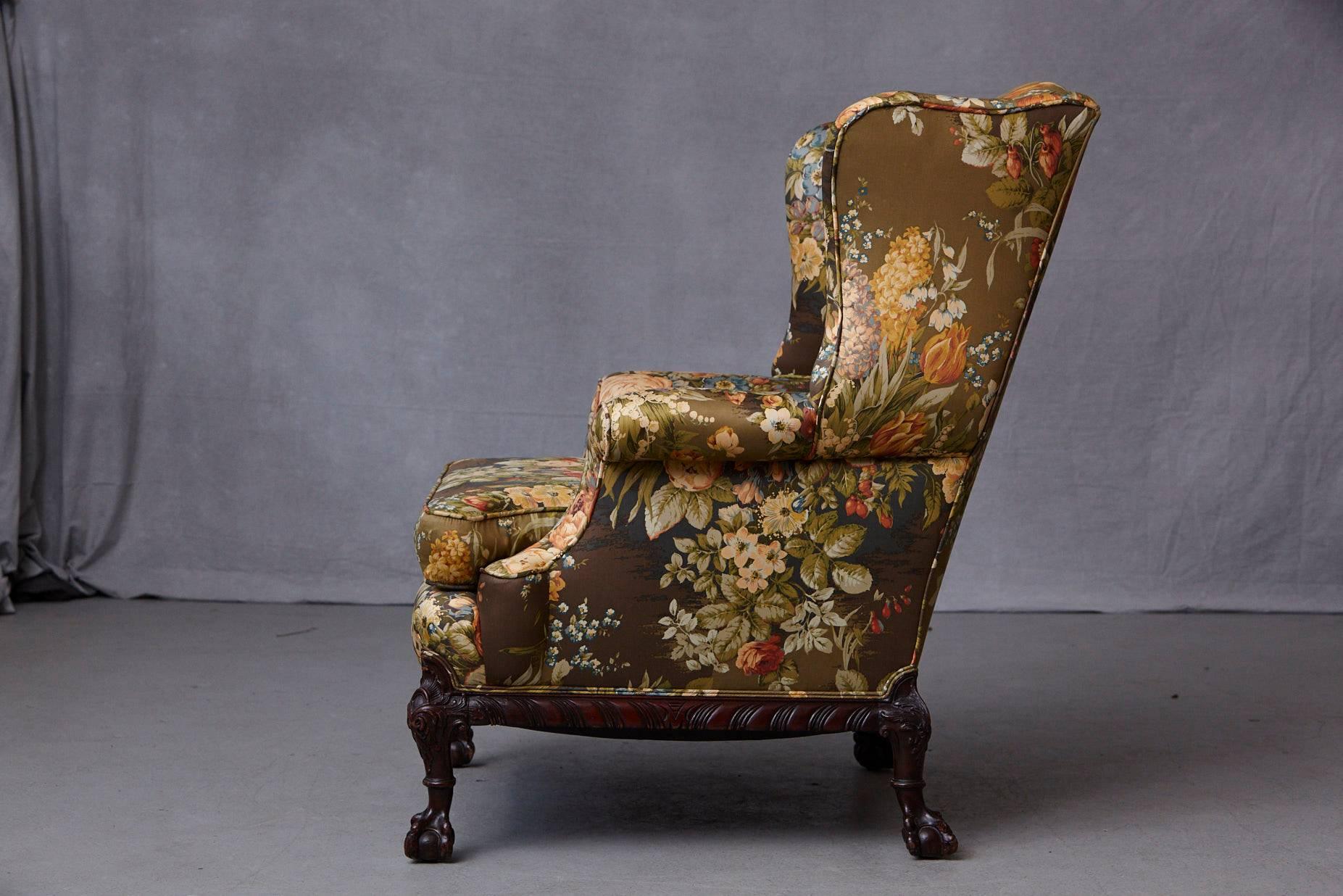 Late 19th Century Chippendale Style mahogany wingback chair, raised on a scrolled frame with short cabriole legs with elaborated acanthus leaves carved knees terminating on ball-and-claw feet.
Upholstered in a floral chintz fabric from Cyrus Clark