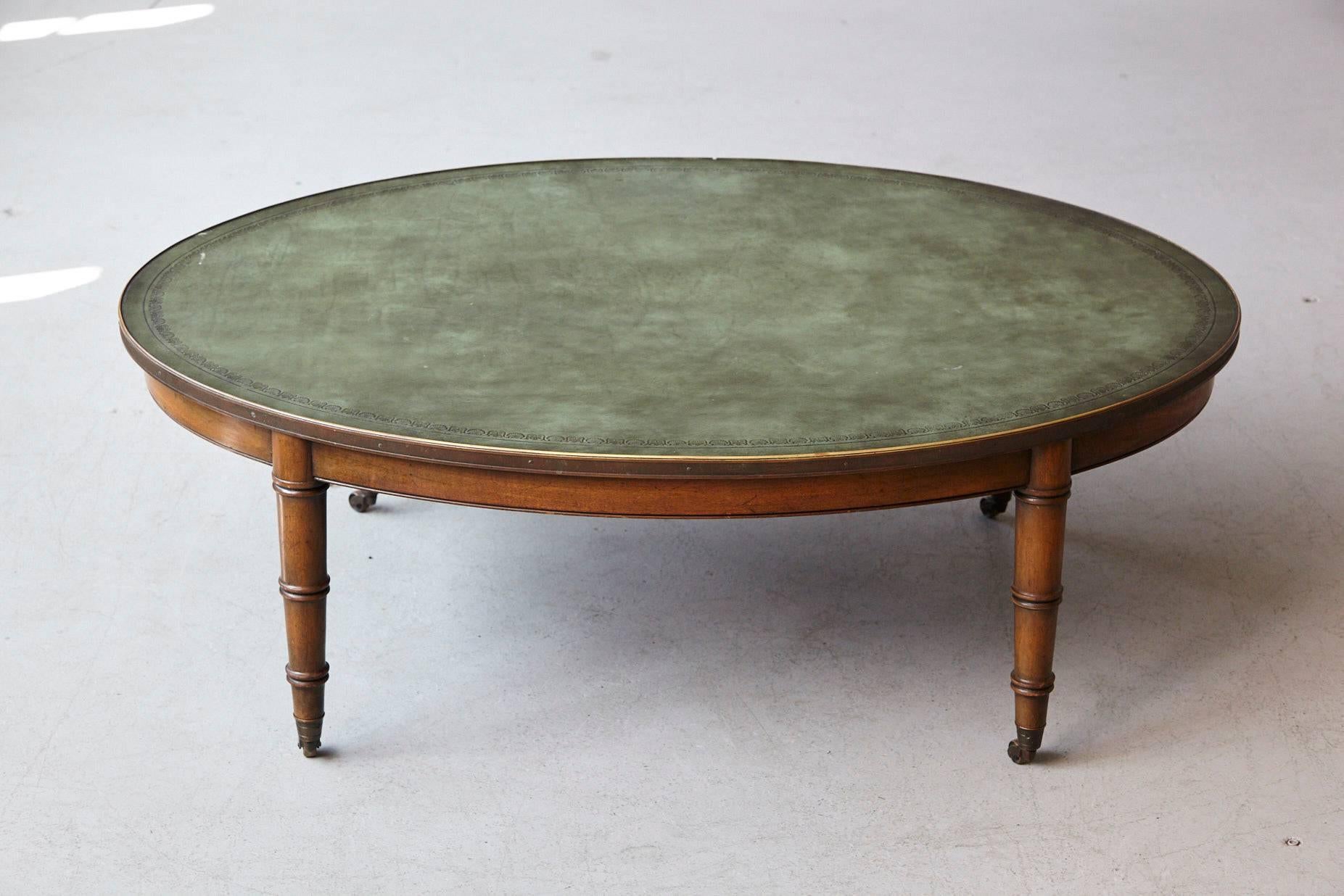 Rare Kittinger oval walnut coffee table with embossed green leather top and brass binding, raised on stylized faux bamboo legs with brass casters.
This table carries the serial number # 1 of the model T347 C.
Some minor scratches to the wood and