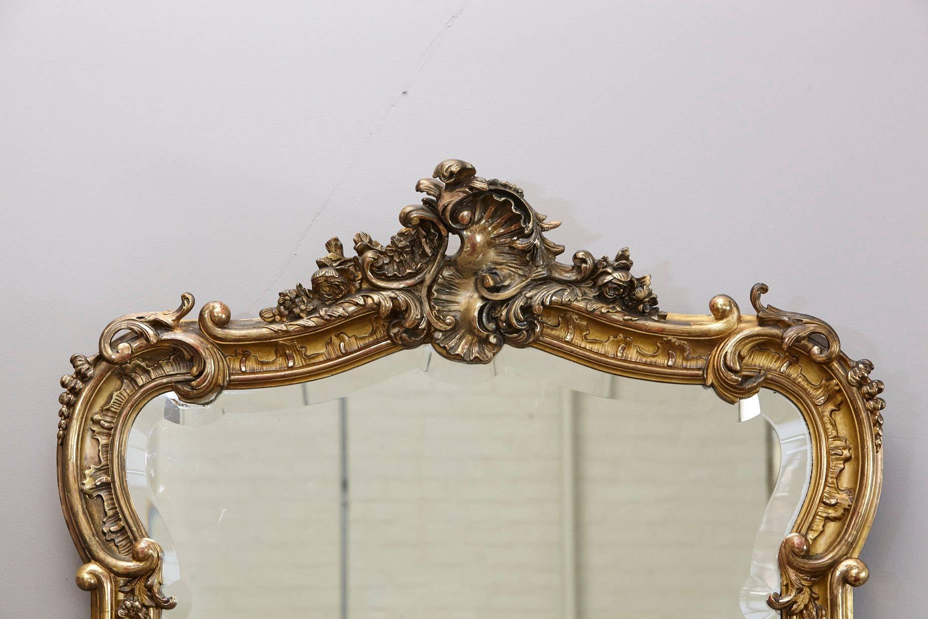 Beautiful 19th century French Rococo mirror with an moulded frame with finely carved foliate scrolling and rosettes, surmounted by an elaborated cresting showing a shell in the center and beveled glass.
Delicate interlacing of curves and counter