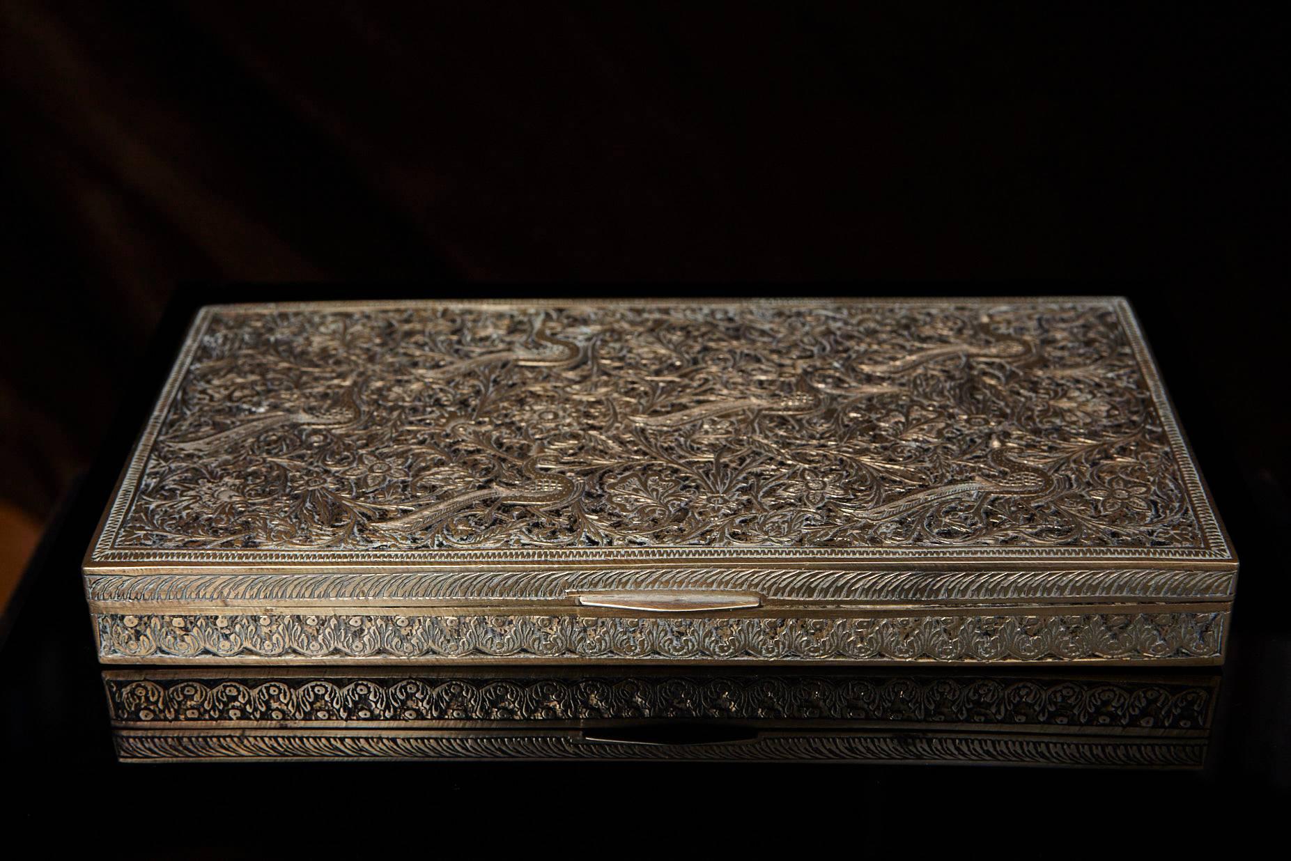 A beautiful antique Persian brass box decorated with ornate engraved designs showing a multitude of flora and fauna in elegant repeating patterns.
The cedar lined box may have been designed as a tabletop cigarette box due to its wide, low design