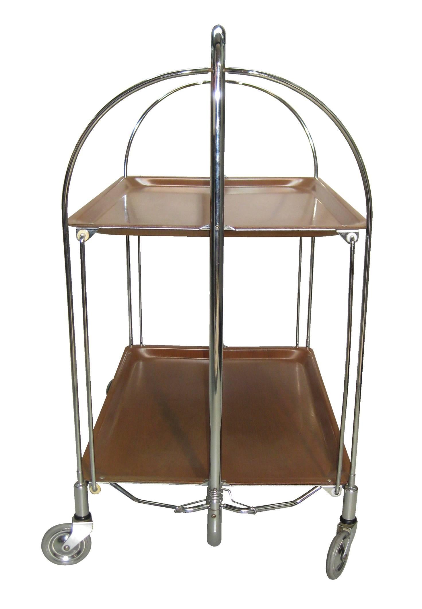 Rare and even delicate in design--but cleverly rugged in its ability to fold for storage--this beautiful Mid-Century cart has been listed by Michael Hogben as one of the 