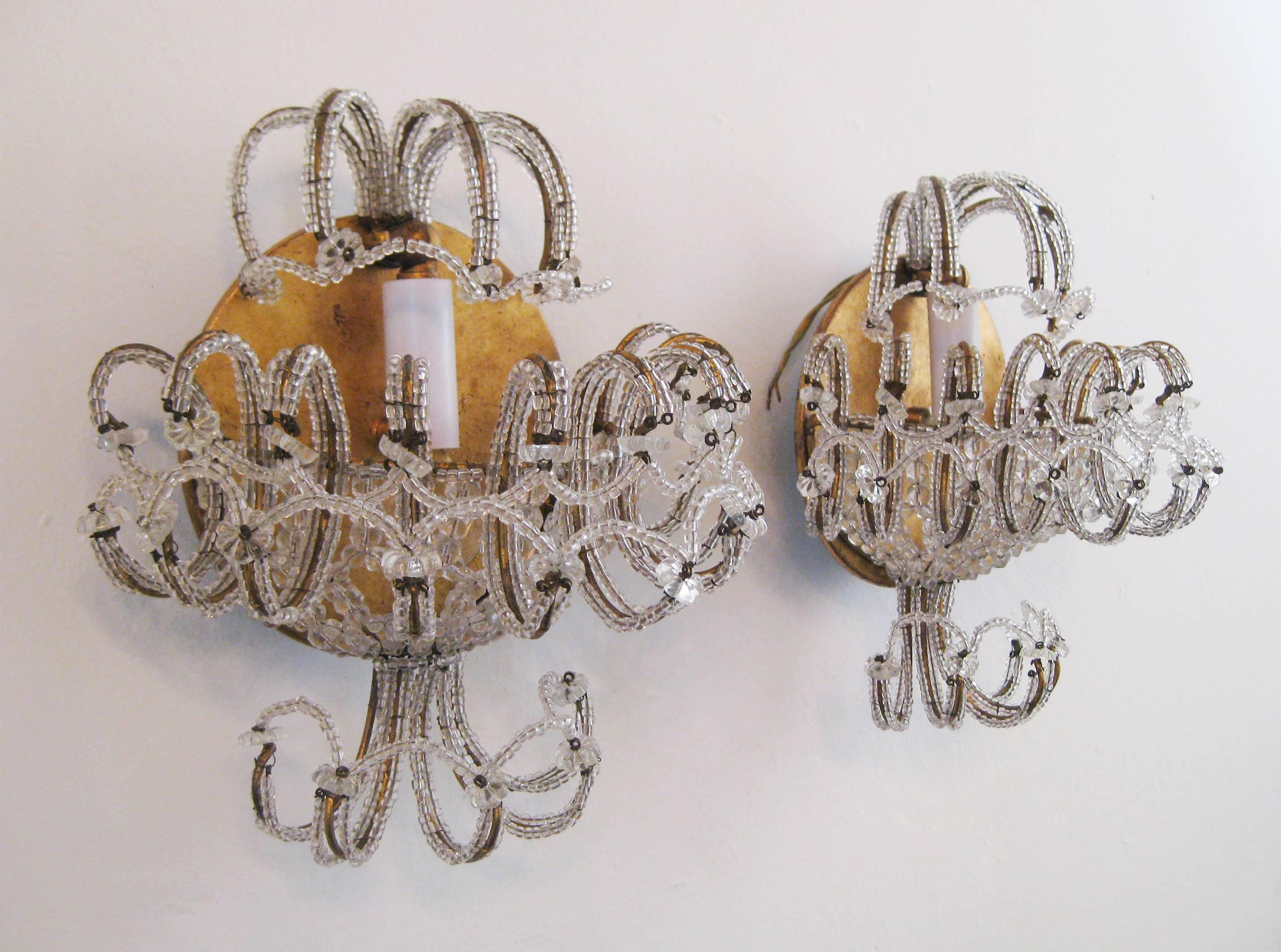 Golden wall lamps trimmed in glass beads, Hollywood Regency style. Signed 