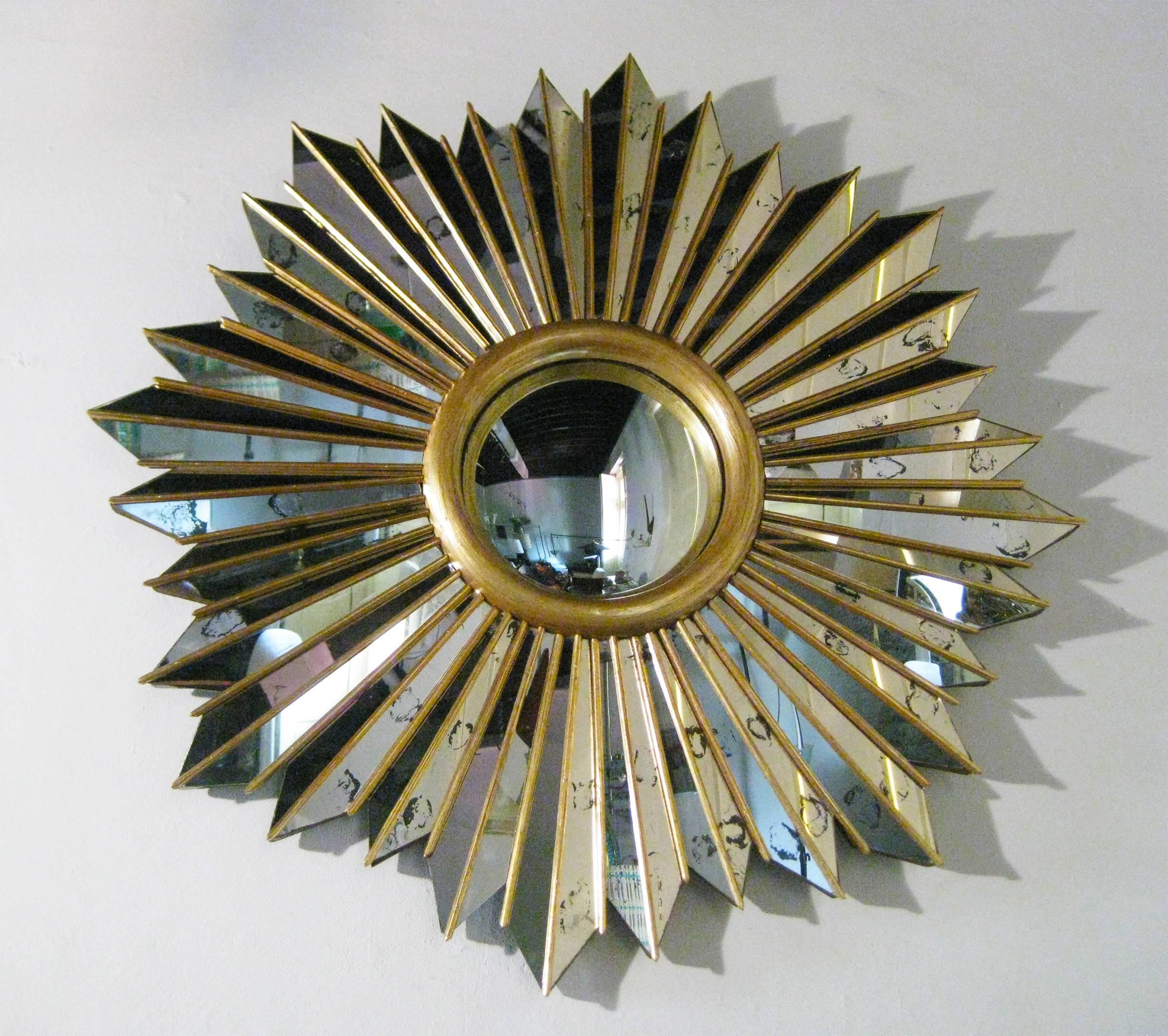 Spectacular and in perfect condition! The basic framing structure, of solid wood adorned in gold leaf, elaborately surrounds a convex mirror with intricately mirrored rays. Note that these rays are not flat; rather, they are joined at an angle,
