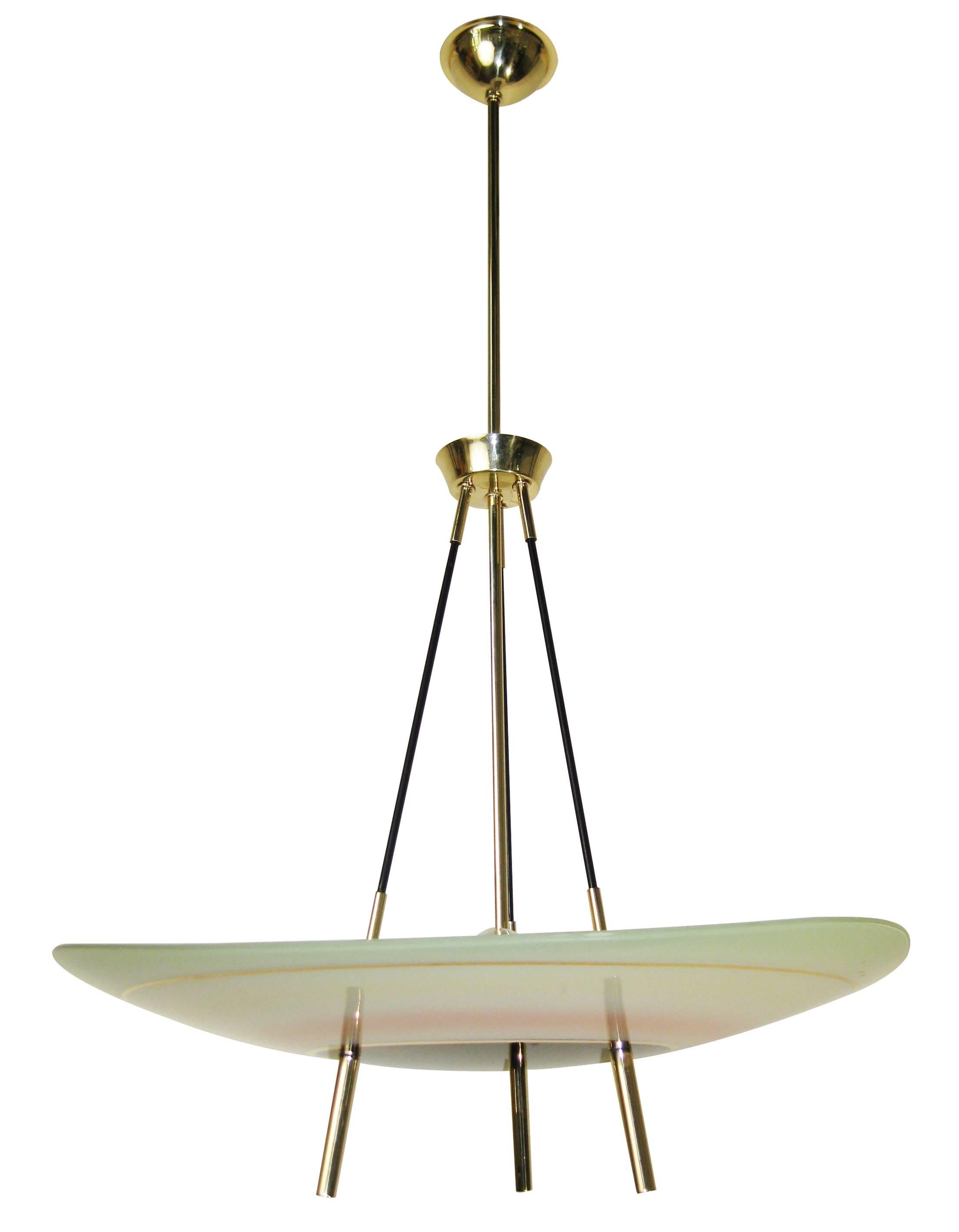 What is striking about the design of this chandelier is not only the ovoid shape of its softly colored glass shade but the unusual manner in which the three stylish brass supports affix to secure it. These subtle details imbue the body of the lamp