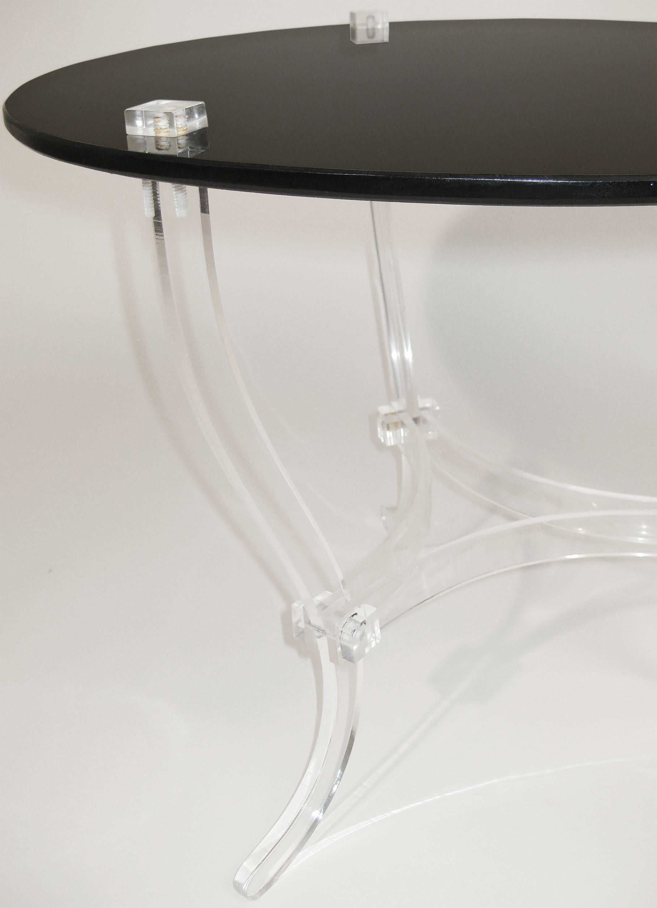 Delicate yet sturdy occasional or cocktail table with serpentine base of Lucite that supports a black glass tabletop. The contrast of the Lucite's transparency with the dense black of the Vitrolite is nothing less than striking. A beautiful