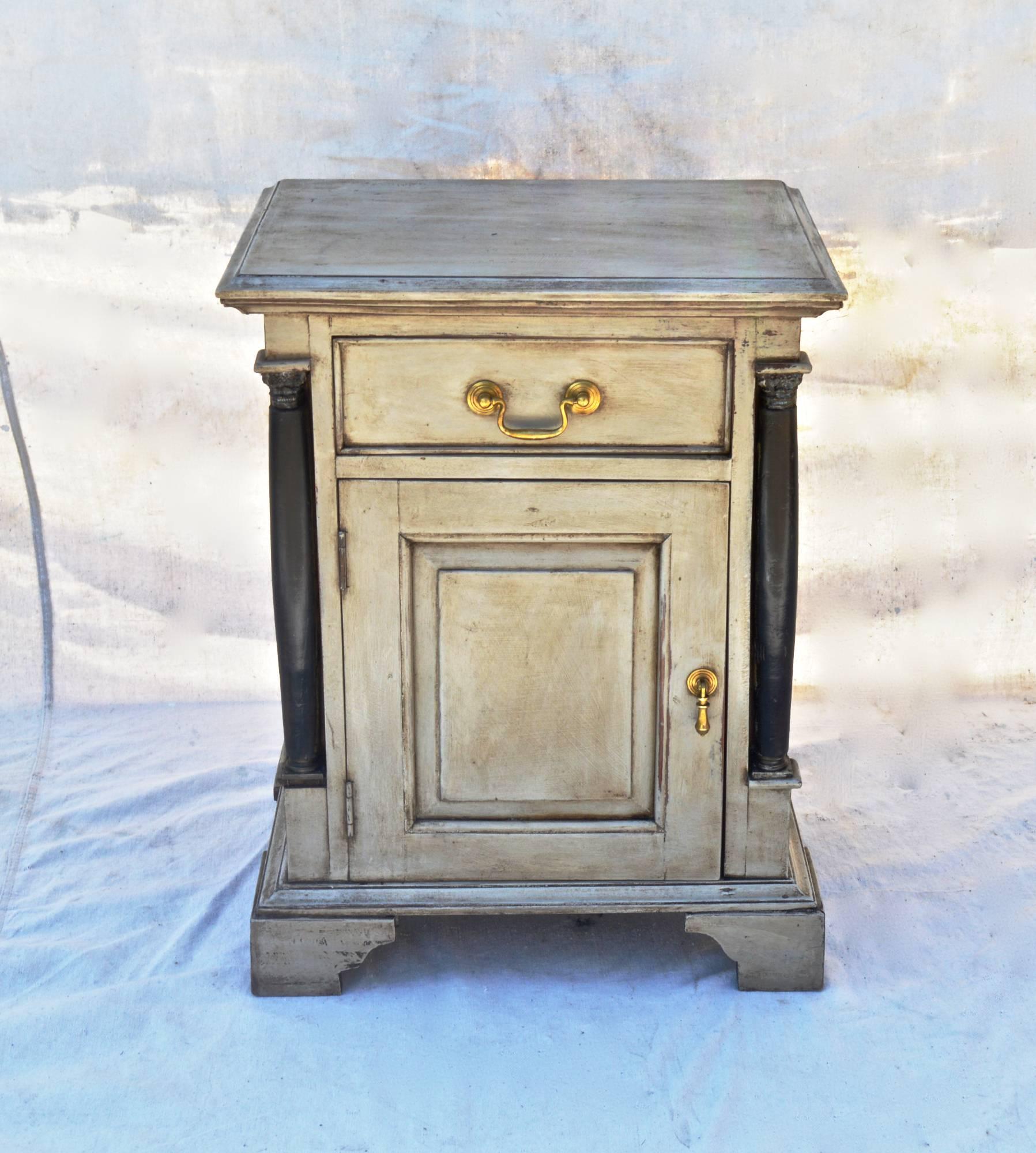 Early 20th Century Continental nightstand having a French washed paint finish. The single drawer is opened by a finely cast bail pull. A matching teardrop pull opens the swinging door to the storage space below. Paneled sides and back. A useful and