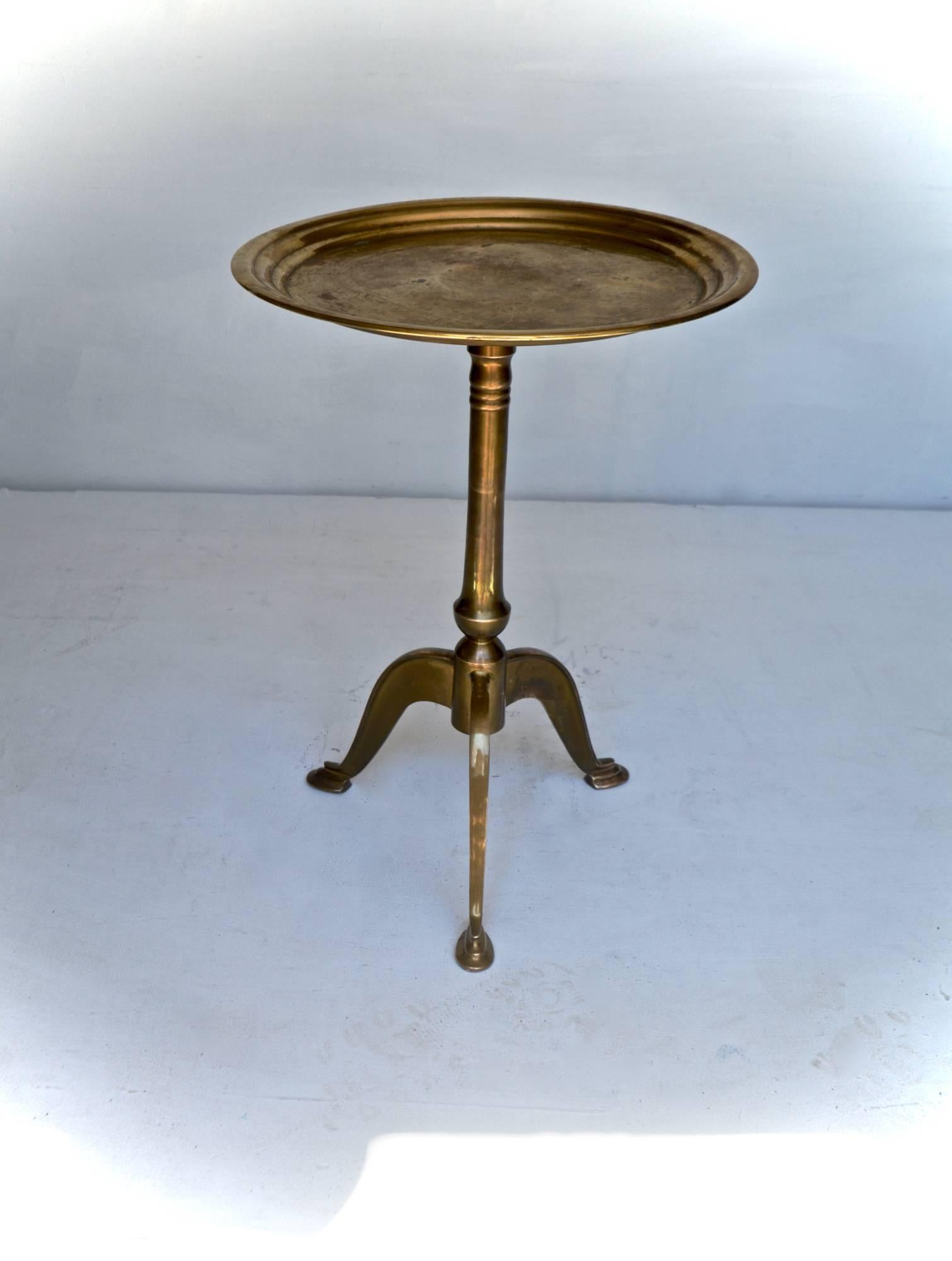 Stunning brass taboret table having a finely cast tripod base. The pedestal table unscrews in half for easy transport. A lovely patina and even tarnish throughout the vintage table.