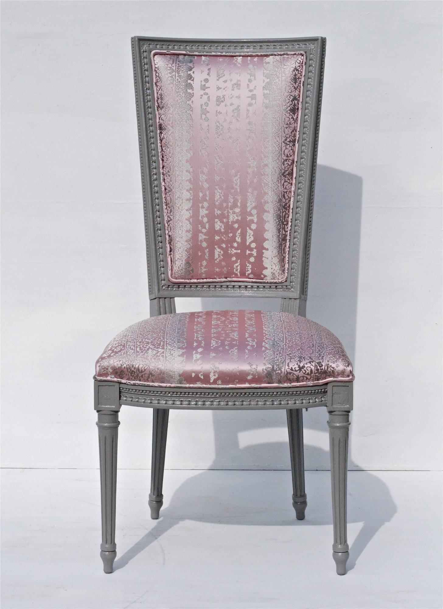 A stunning set of vintage Louis XVI high back dining chairs hand lacquered in fine paints of Europe Holland Lac and dressed up in a silk / satin blended fabric by Donghia. The high contrast combination of grey and pink tones is a feast for the eyes