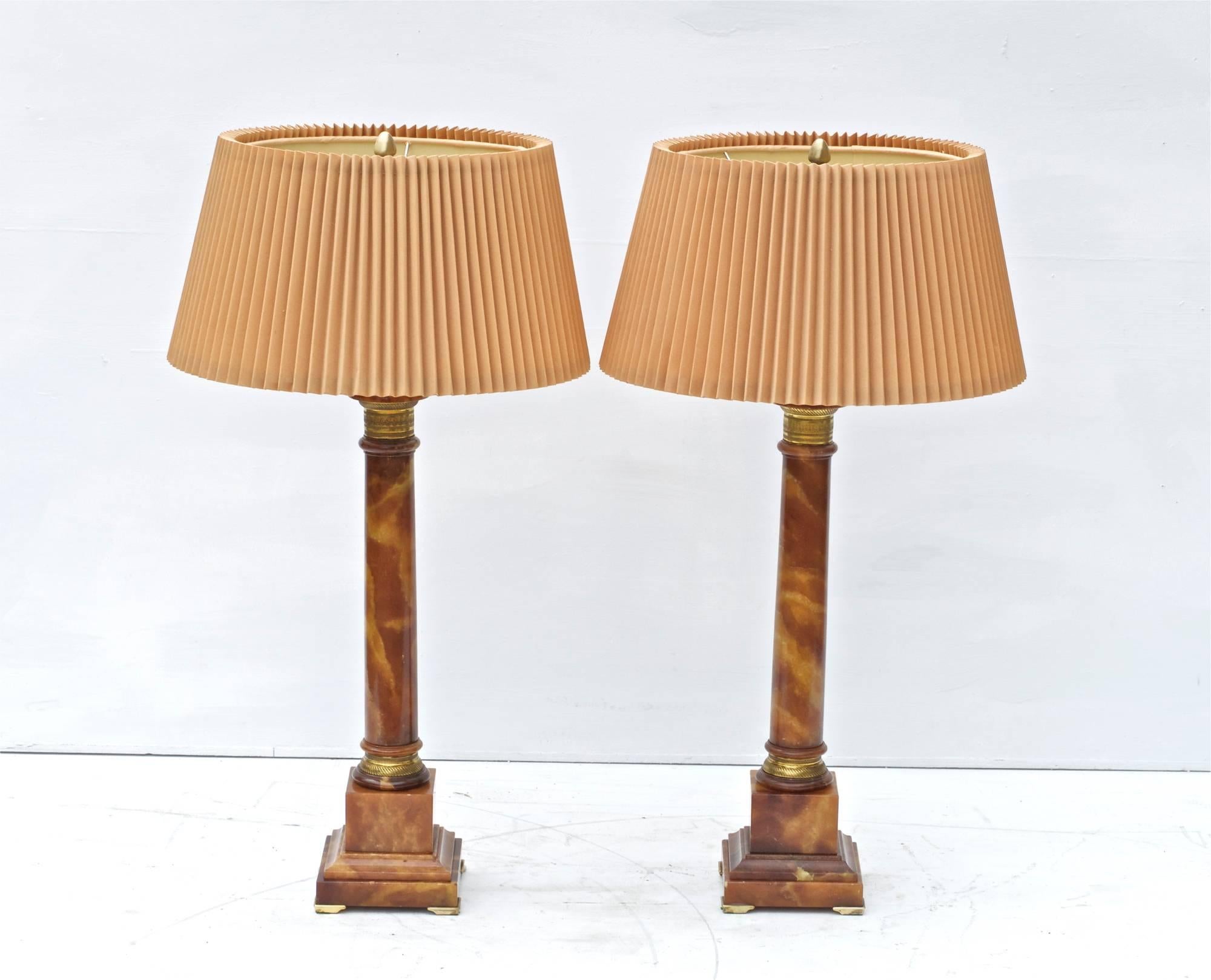 Pair of rare and striking marble lamps by the Marbro Lamp Co, circa 1960. The column form lamps are definitively in the French Empire taste having dashingly good looking cast brass accents throughout. Original parts, shades and diffusors. In