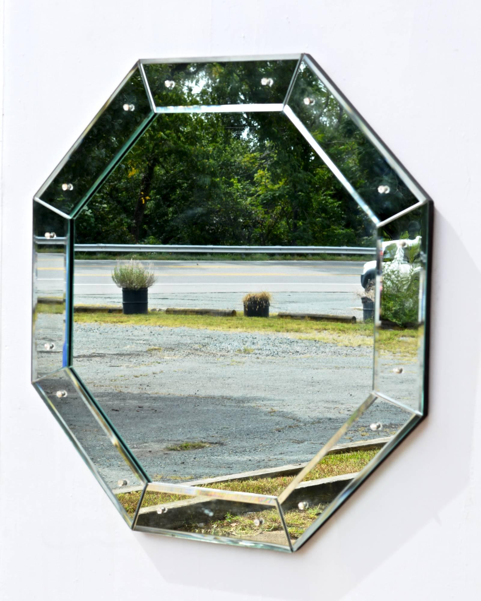 Glamorous late 1970s octagonal mirror. Outer frame is in the Venetian style having geometric mirror glass panels. Simple and chic.
