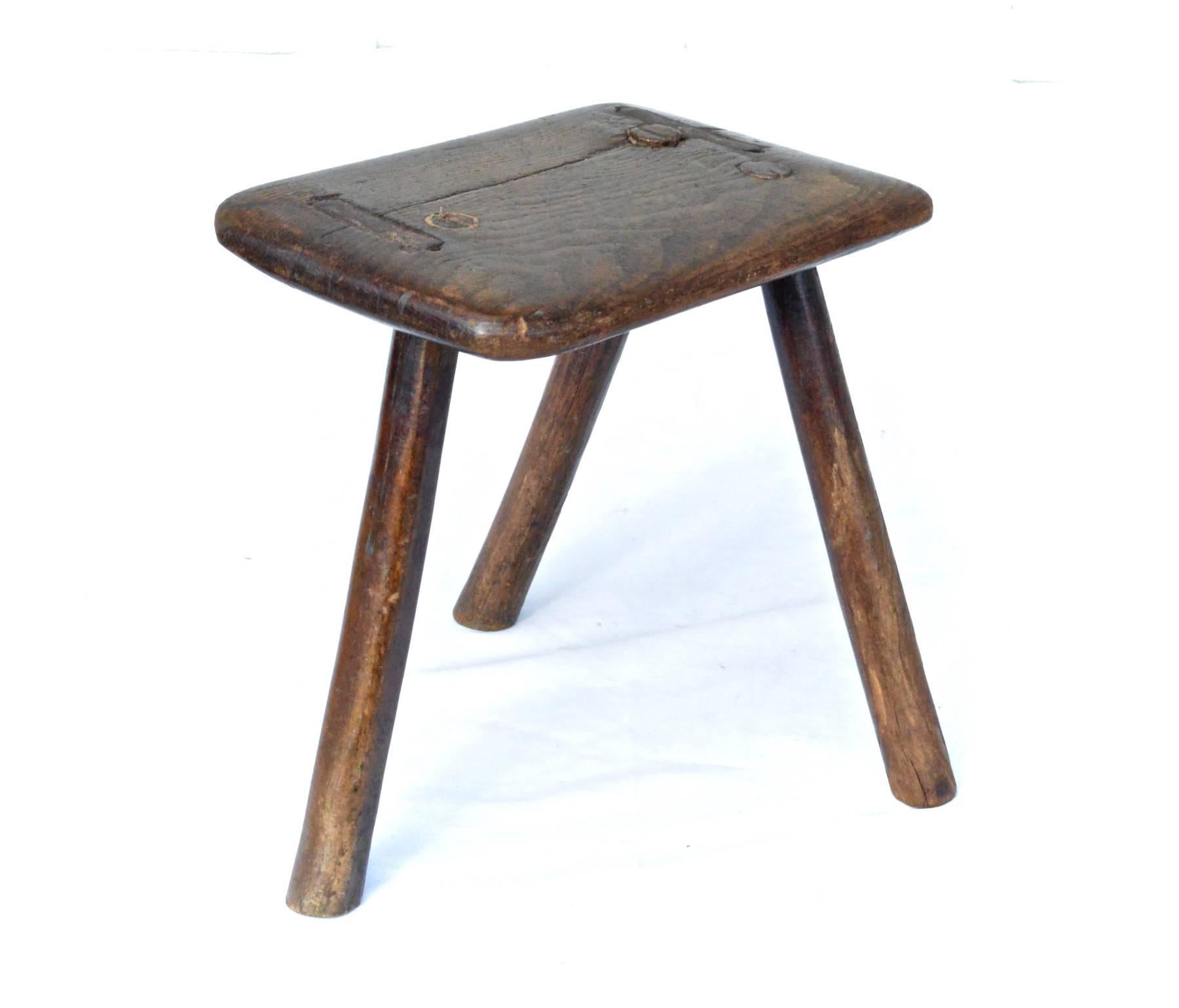 An interesting little 18th century footstool or plant stand of pine. A plank top houses three tripod shaped legs. The surface is silky and smooth with a great deal of natural patina.
